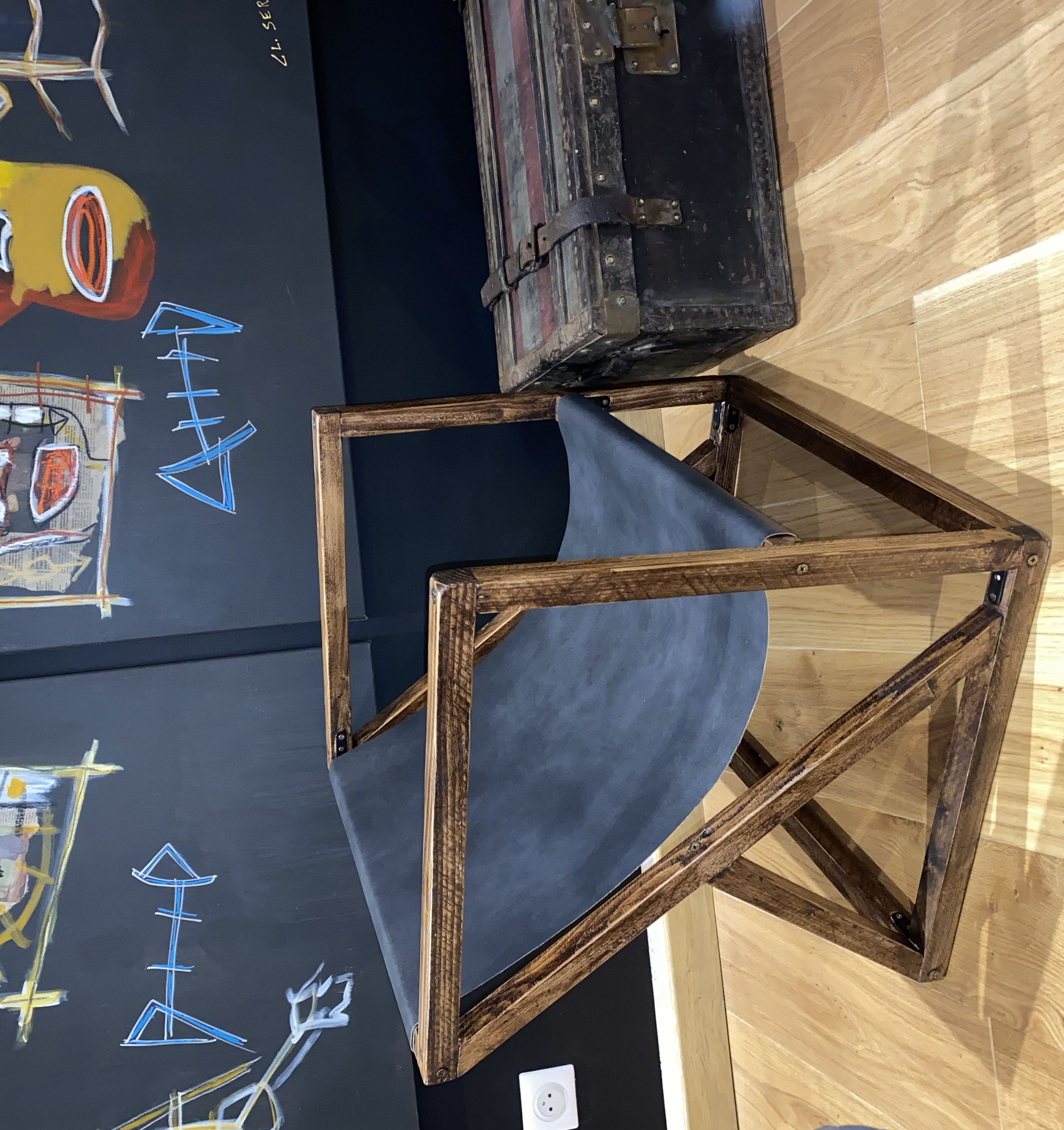 La chaise terminée : structure en bois teinté à lignes obliques et assise de cuir noir