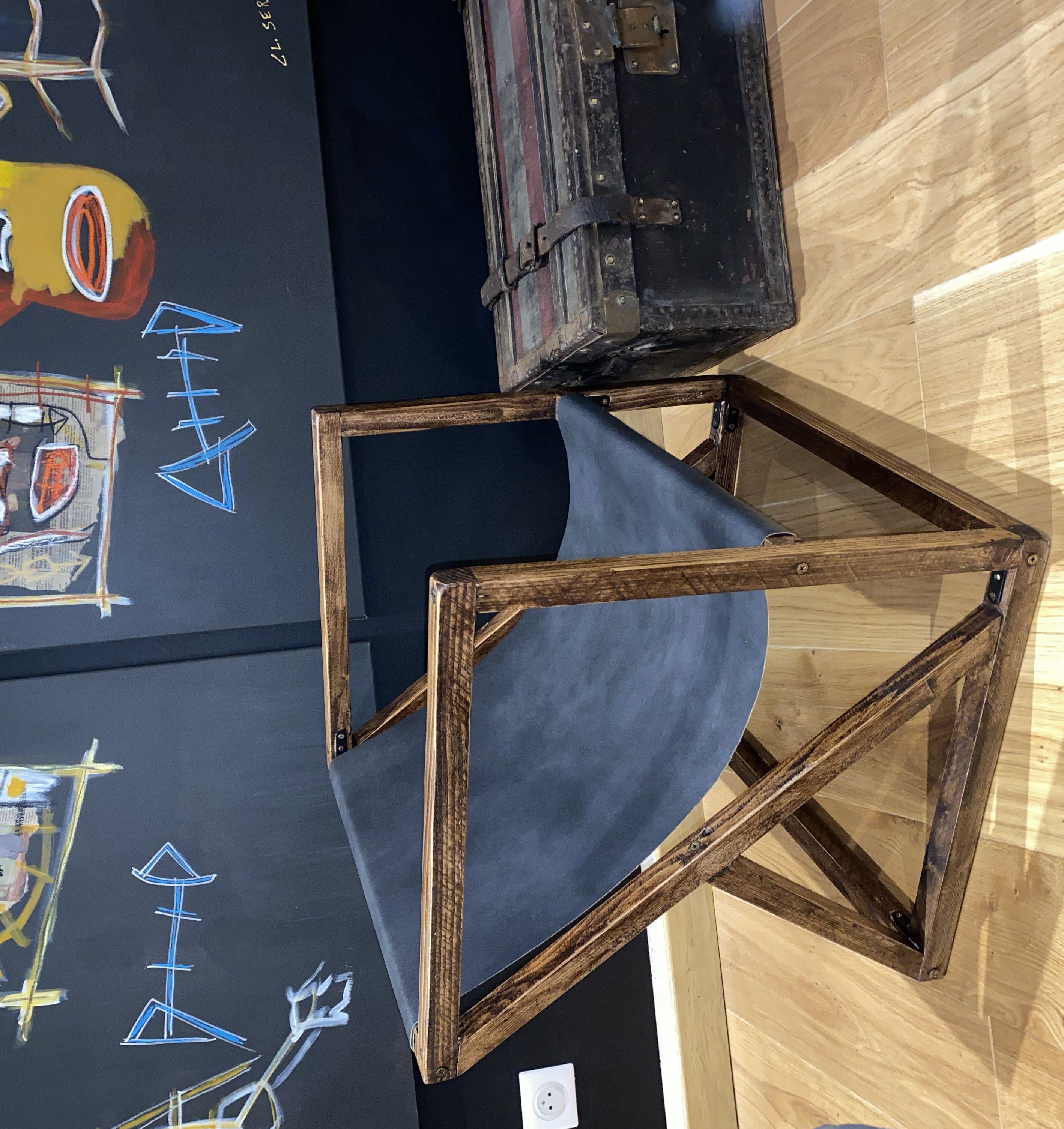 La chaise terminée : structure en bois teinté à lignes obliques et assise de cuir noir