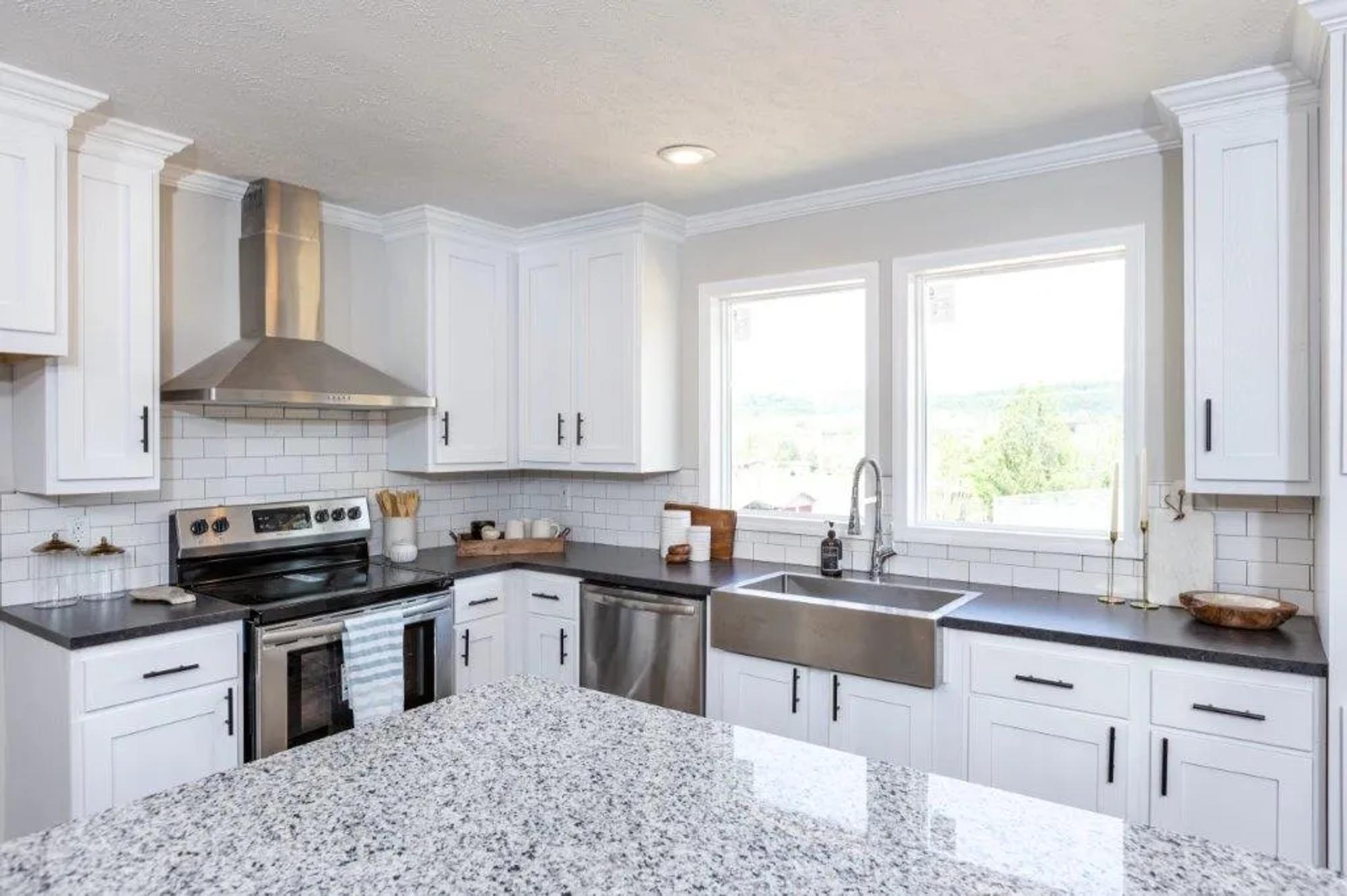 Close-up of kitchen with white cabinets, drawers, and white brick backsplash