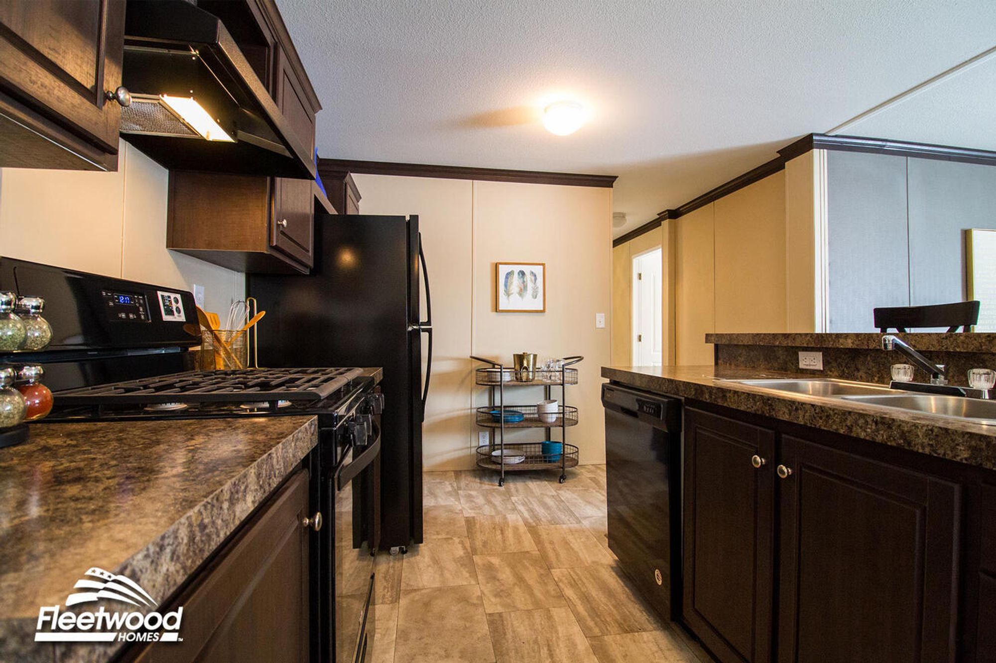 Kitchen with dark wood cabinets, black appliances, granite-style countertops, and a double sink on the island.