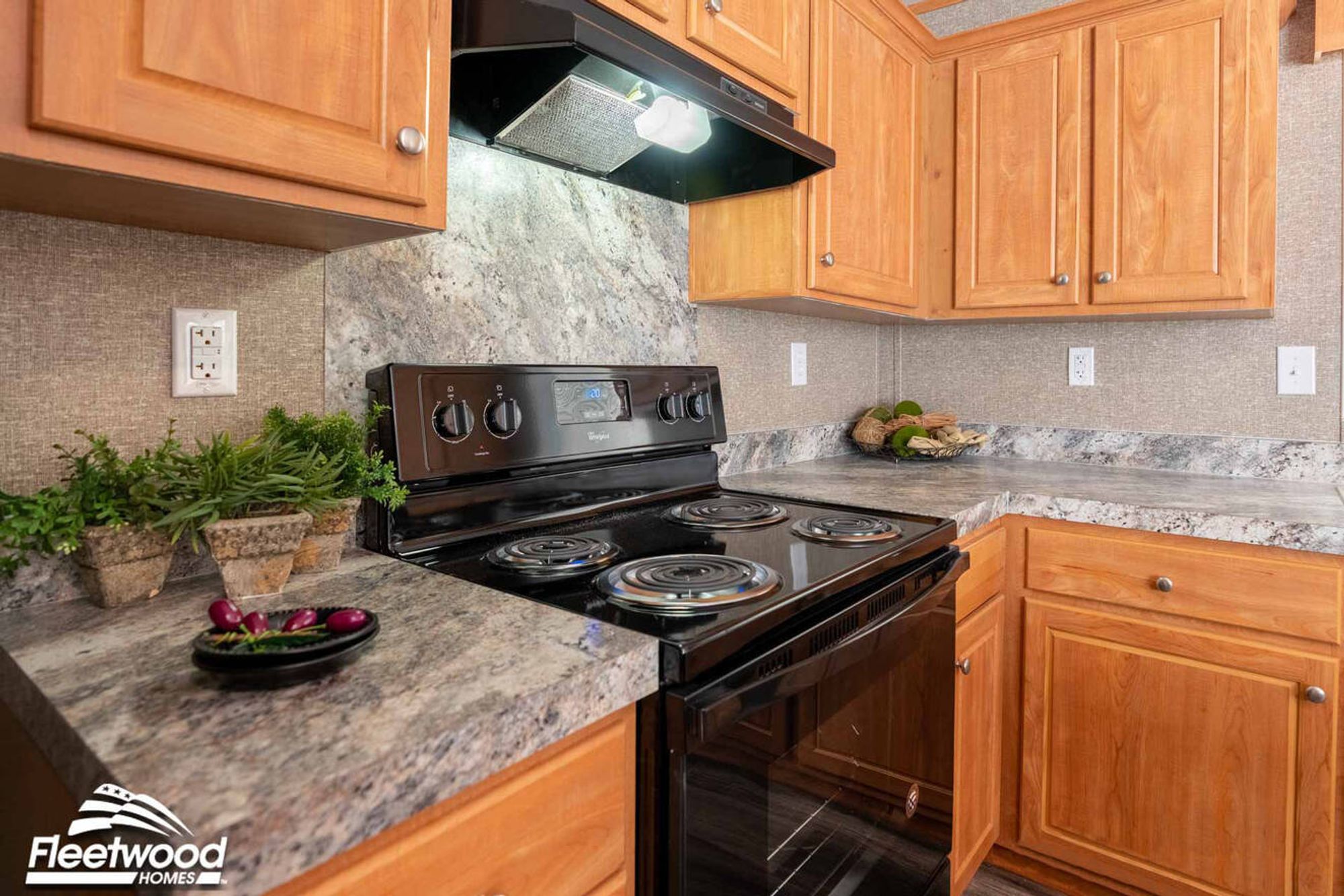 Kitchen with wood cabinets, marble-look countertops, and a black stove with matching range hood.