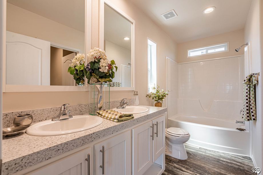 Partial view of the bathroom with a double-sink countertop and bathtub-shower combination.