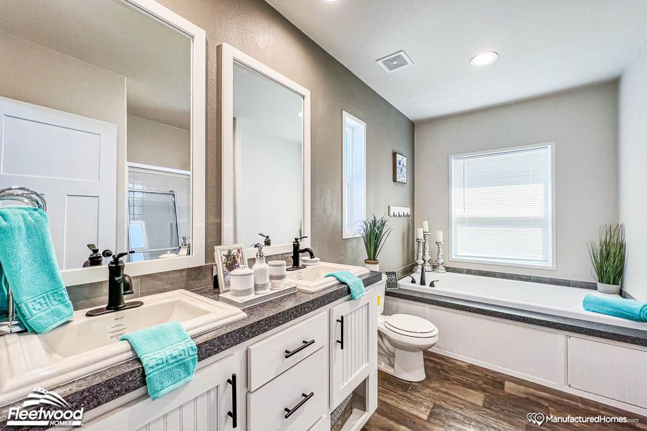 Close-up of a bathroom with a large bathtub and a spacious double-sink countertop.