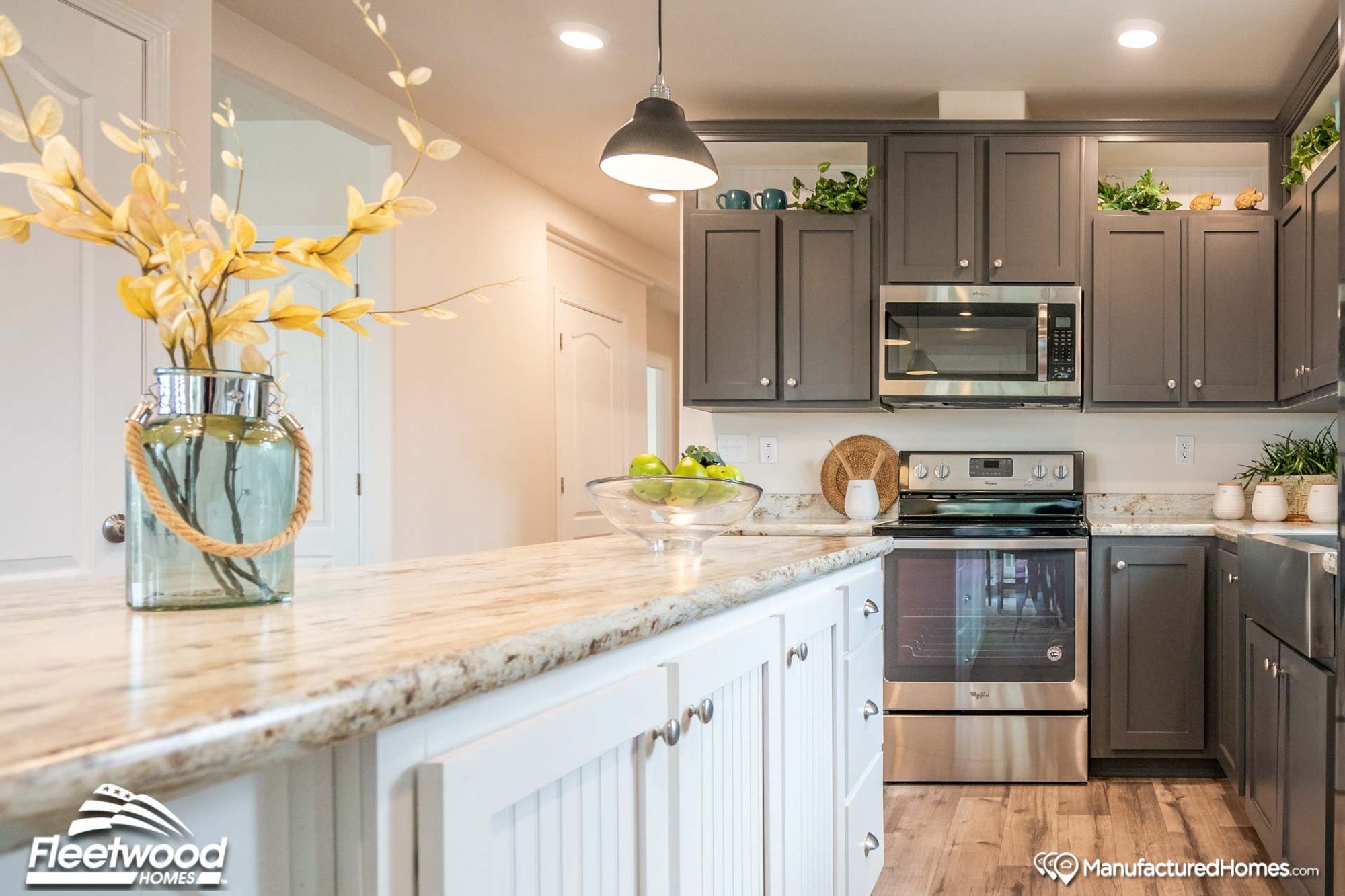Close-up shot of a kitchen’s oven, adjacent counter space, cabinets above, and a partial view of the island.