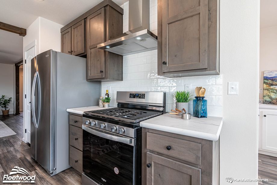 Close-up view of a kitchen’s oven sink, adjacent countertops, and fridge.