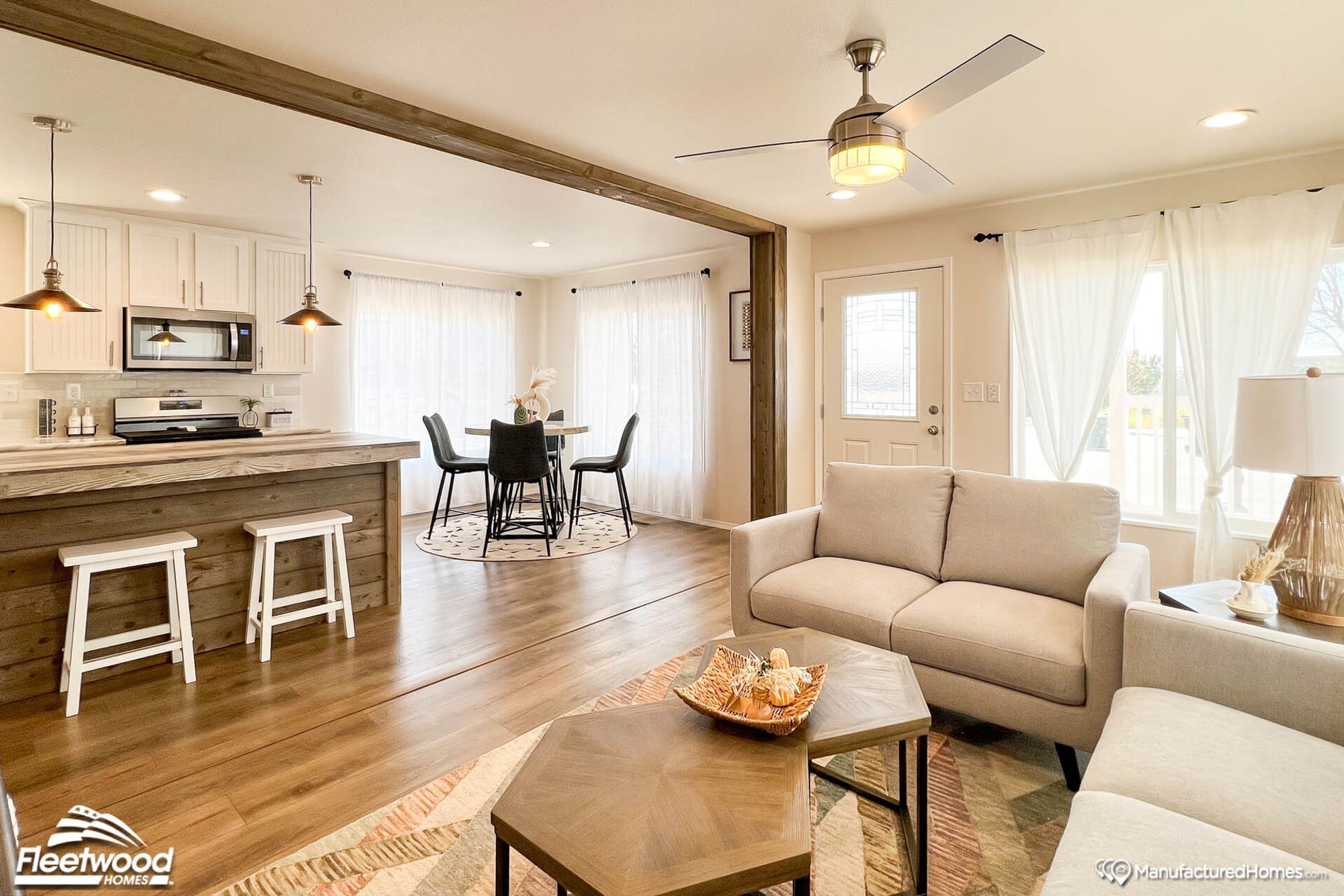 Open concept kitchen, dining room, and living room. The kitchen has an island with two white stools.