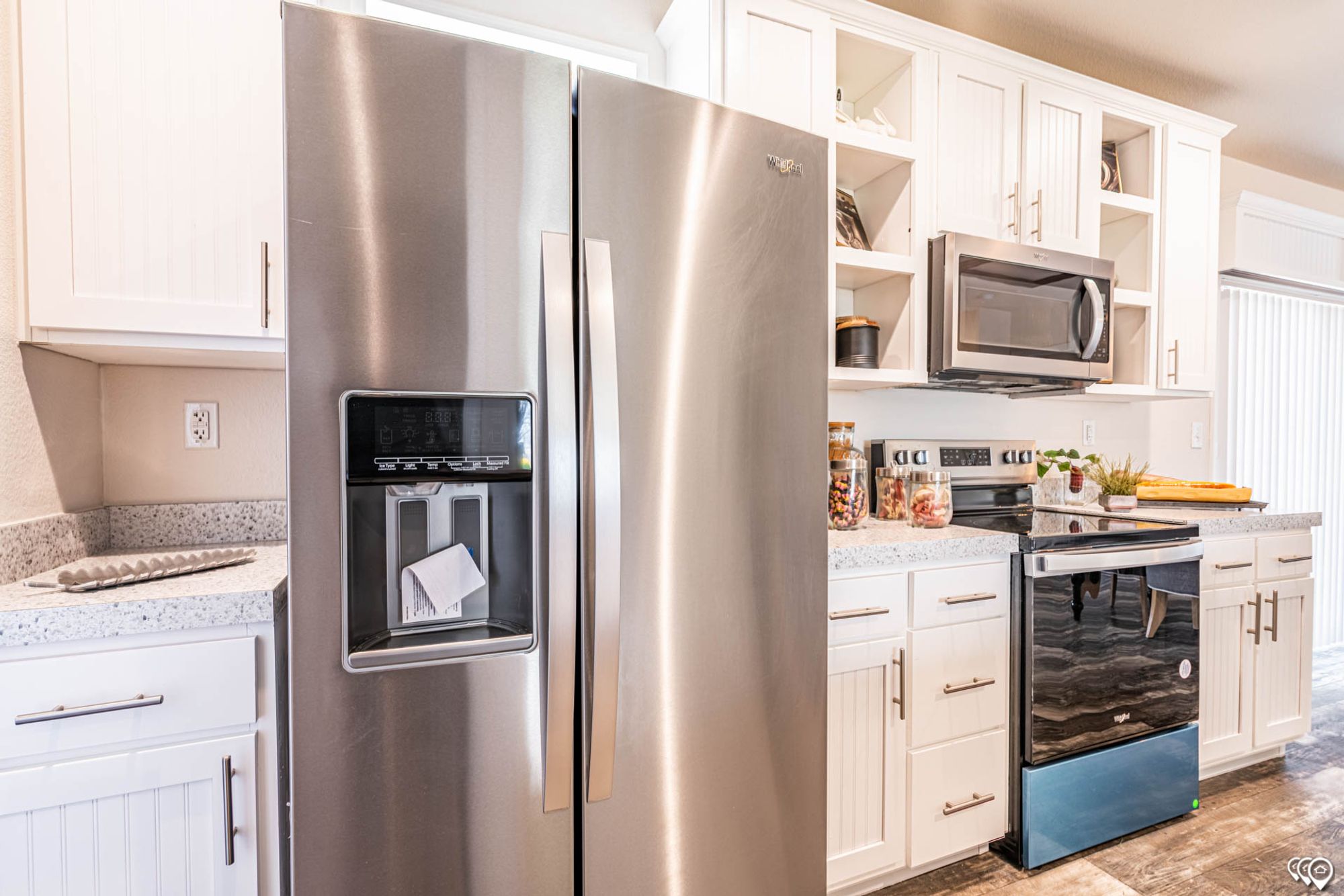 Close-up view of a kitchen with white cabinets, a refrigerator, overhead microwave, and oven.