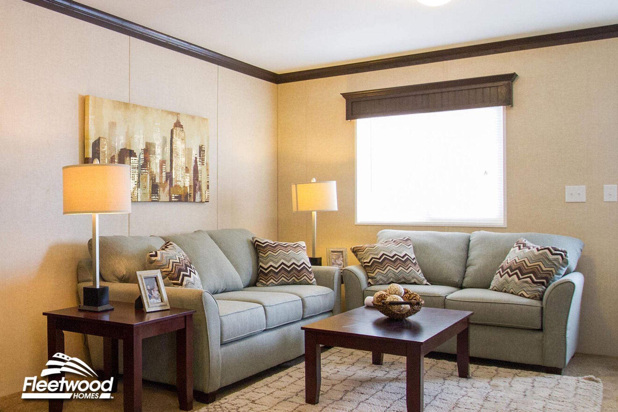 Cozy living room with beige walls, sofa set, coffee table, lamps, and window by the front door.
