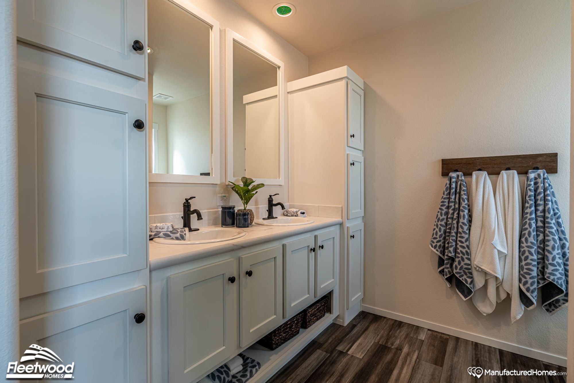 Double sink with two large end cabinets and four towel hooks on the wall.