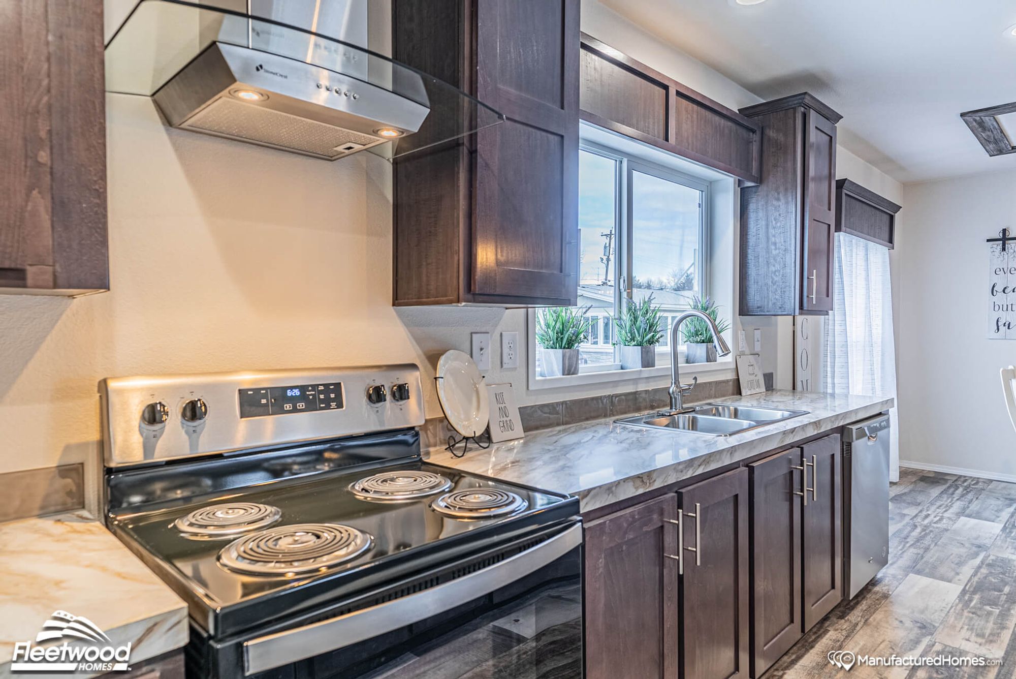 Close-up of a kitchen with brown cabinets, showcasing an oven and a sink.