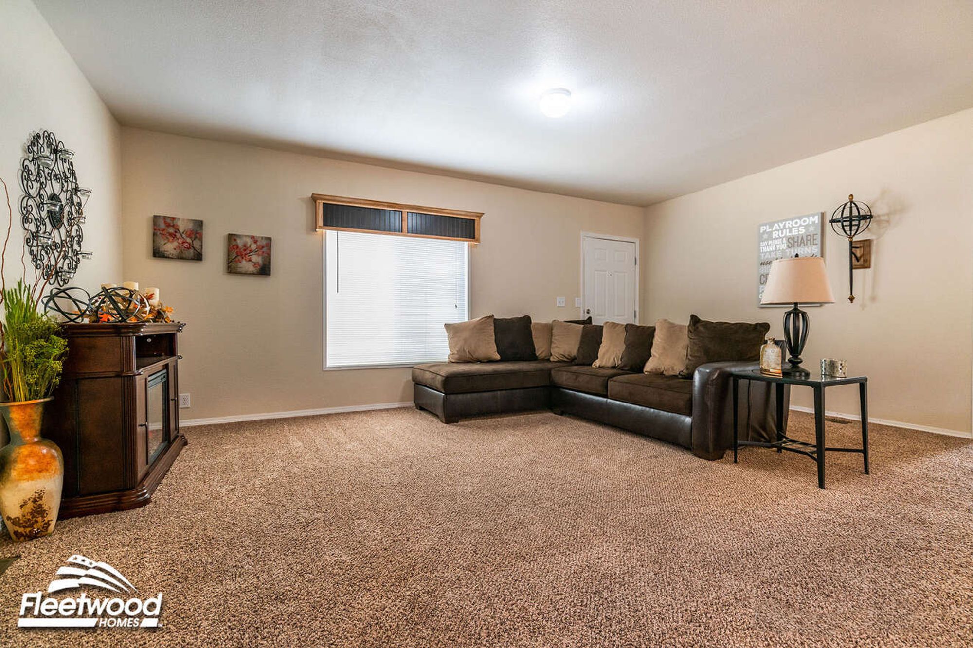 Large open front room with a large couch, a side table, and a fire place.