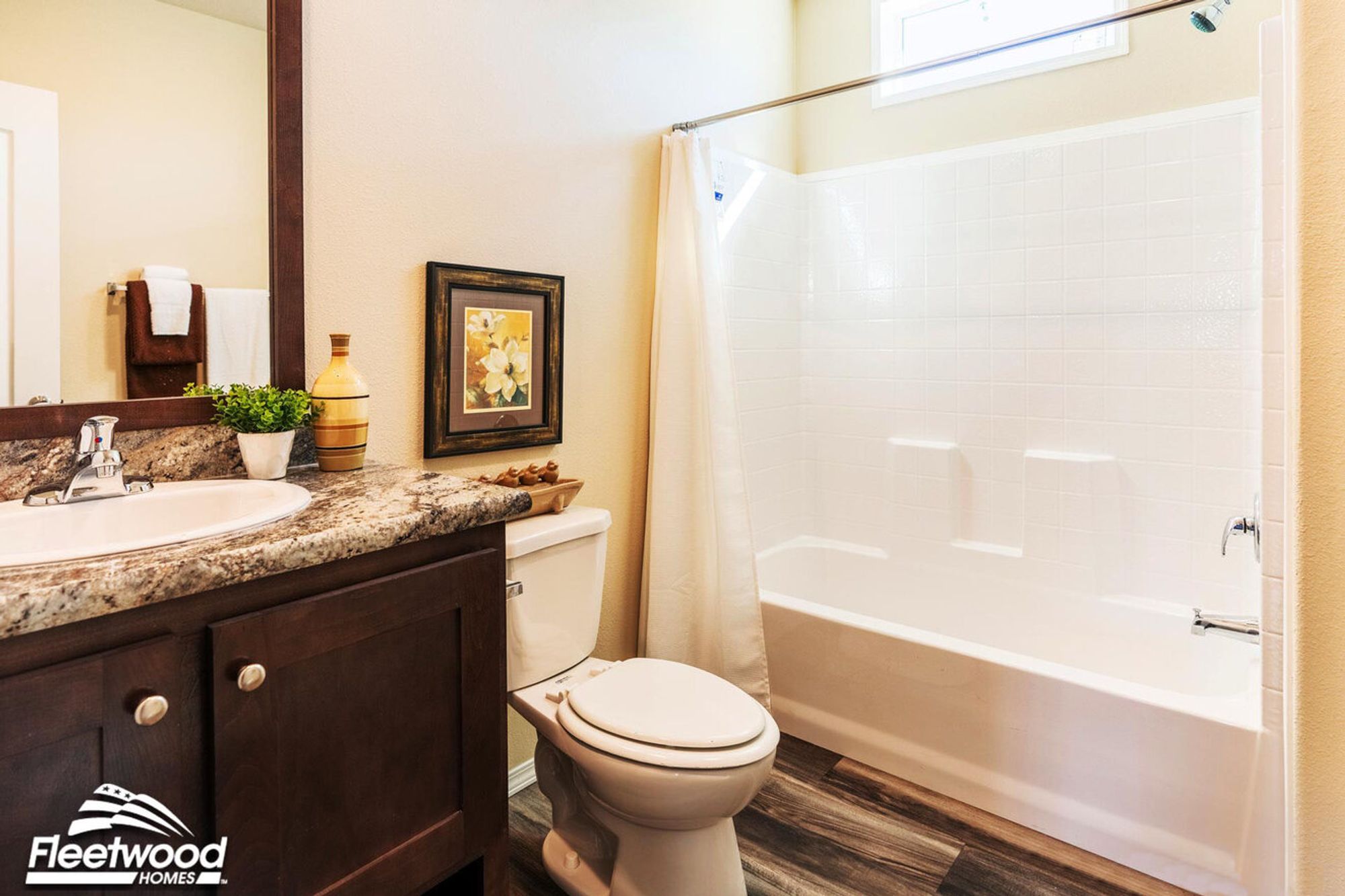 Bathroom with dark wood vanity, granite countertop, toilet, and a white shower-tub combo with curtain.