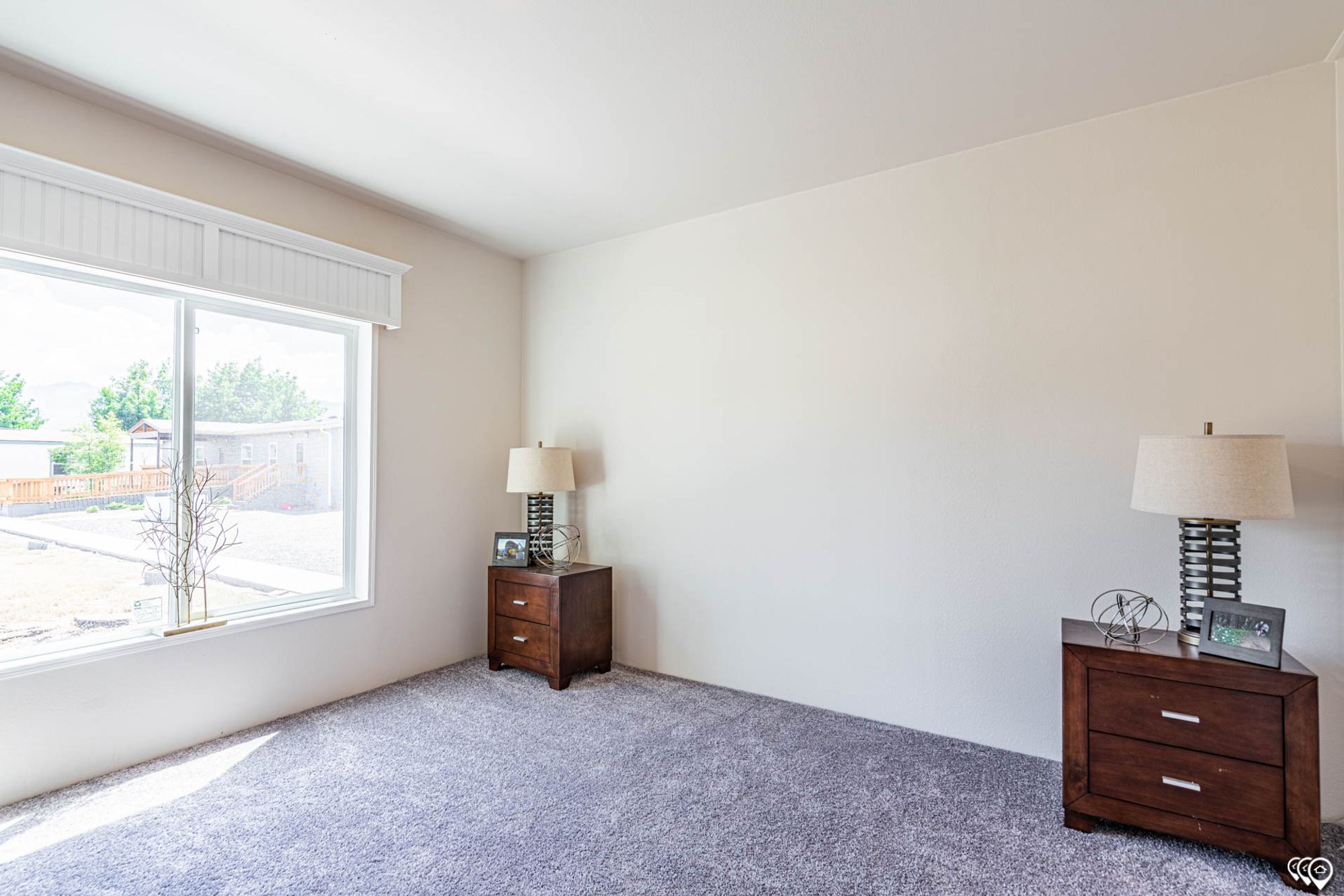 Mostly empty mid-sized bedroom with two side tables.