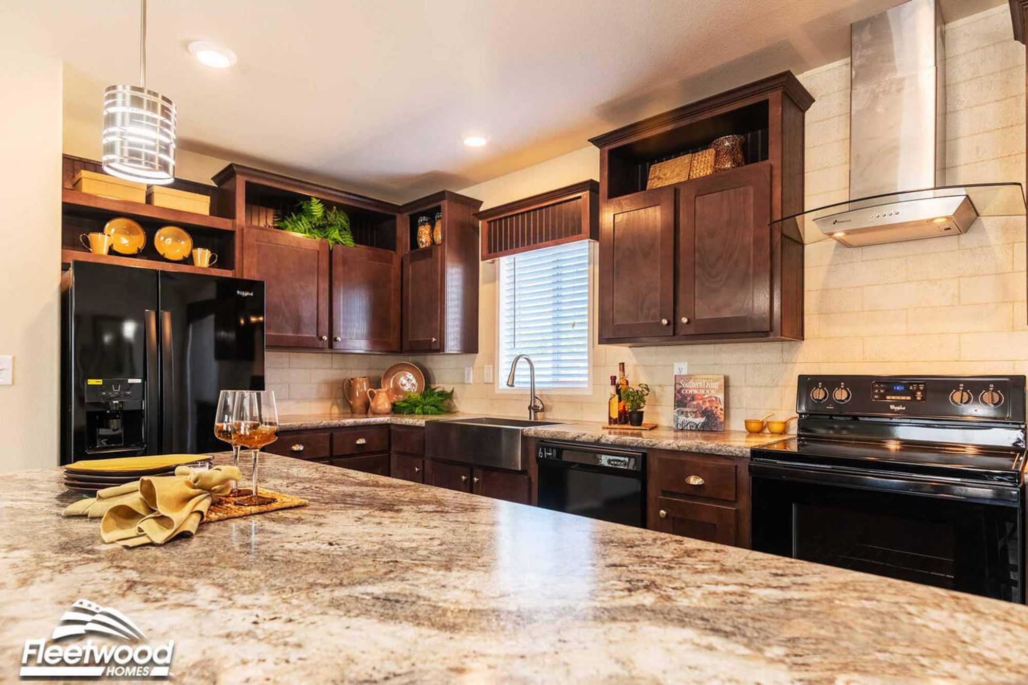 Kitchen, and living area with dark wood cabinets, center island, modern lighting.