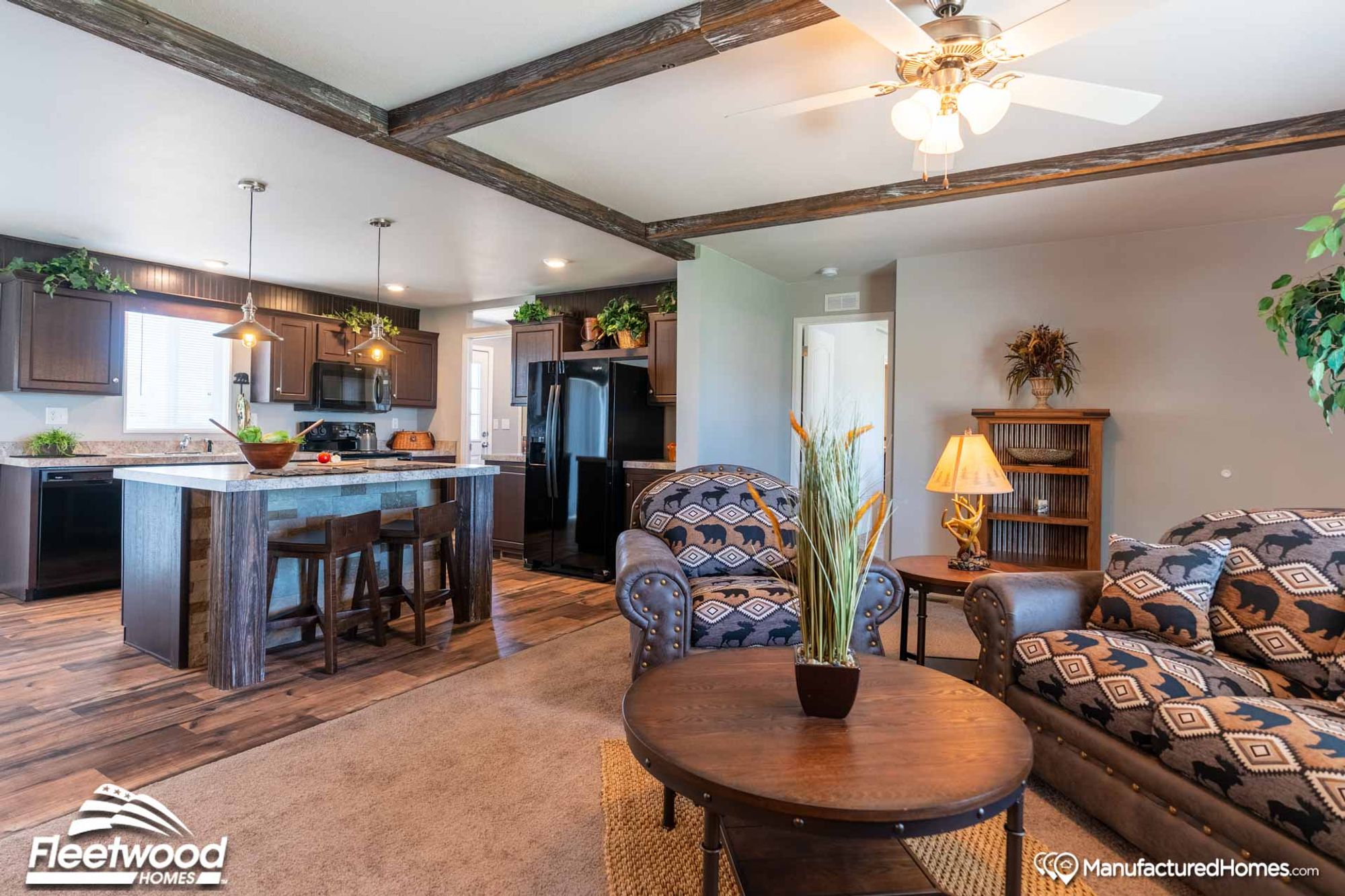 An open concept kitchen, living room, and dining room. The living room is mid-sized with a couch, a coffee table, two side tables, and two chairs.
