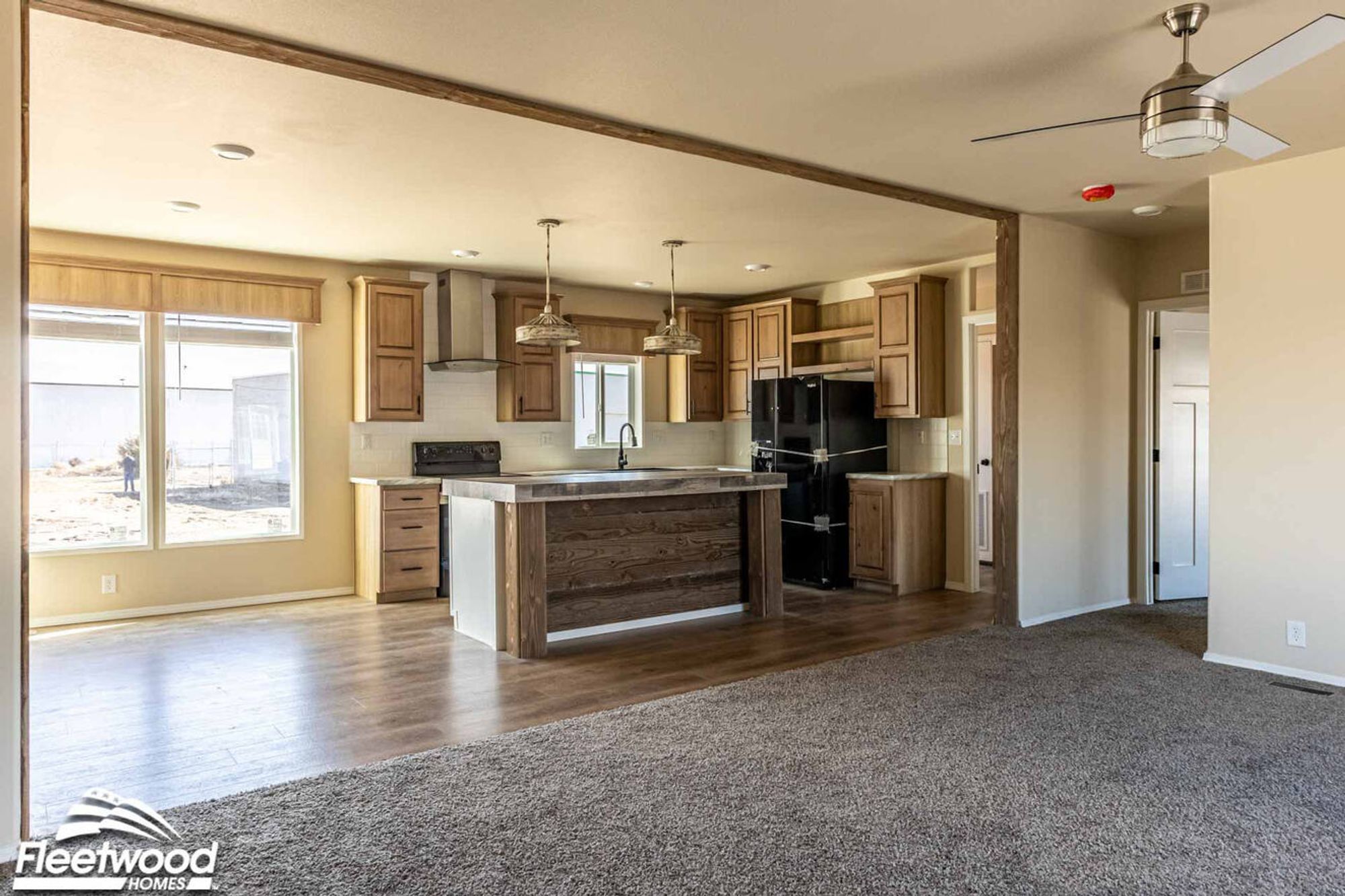 Kitchen with natural wood cabinetry, black appliances, farmhouse sink, and a rustic wood island with pendant lighting.