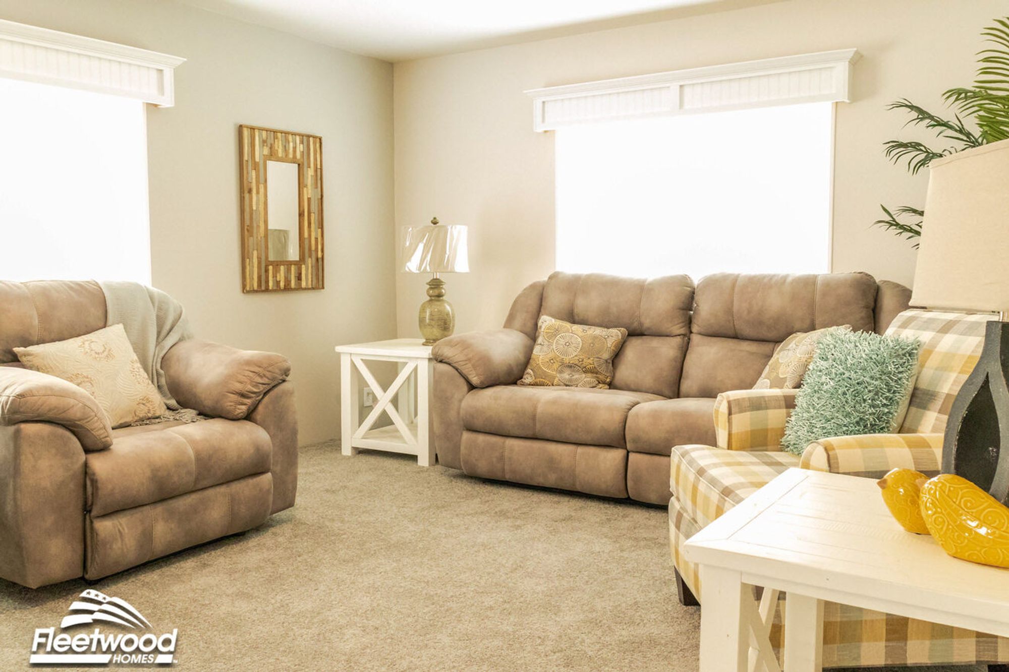 Bright and cozy living room with plush tan seating, a white side table, plaid armchair, and decorative pillows in a neutral and pastel palette.