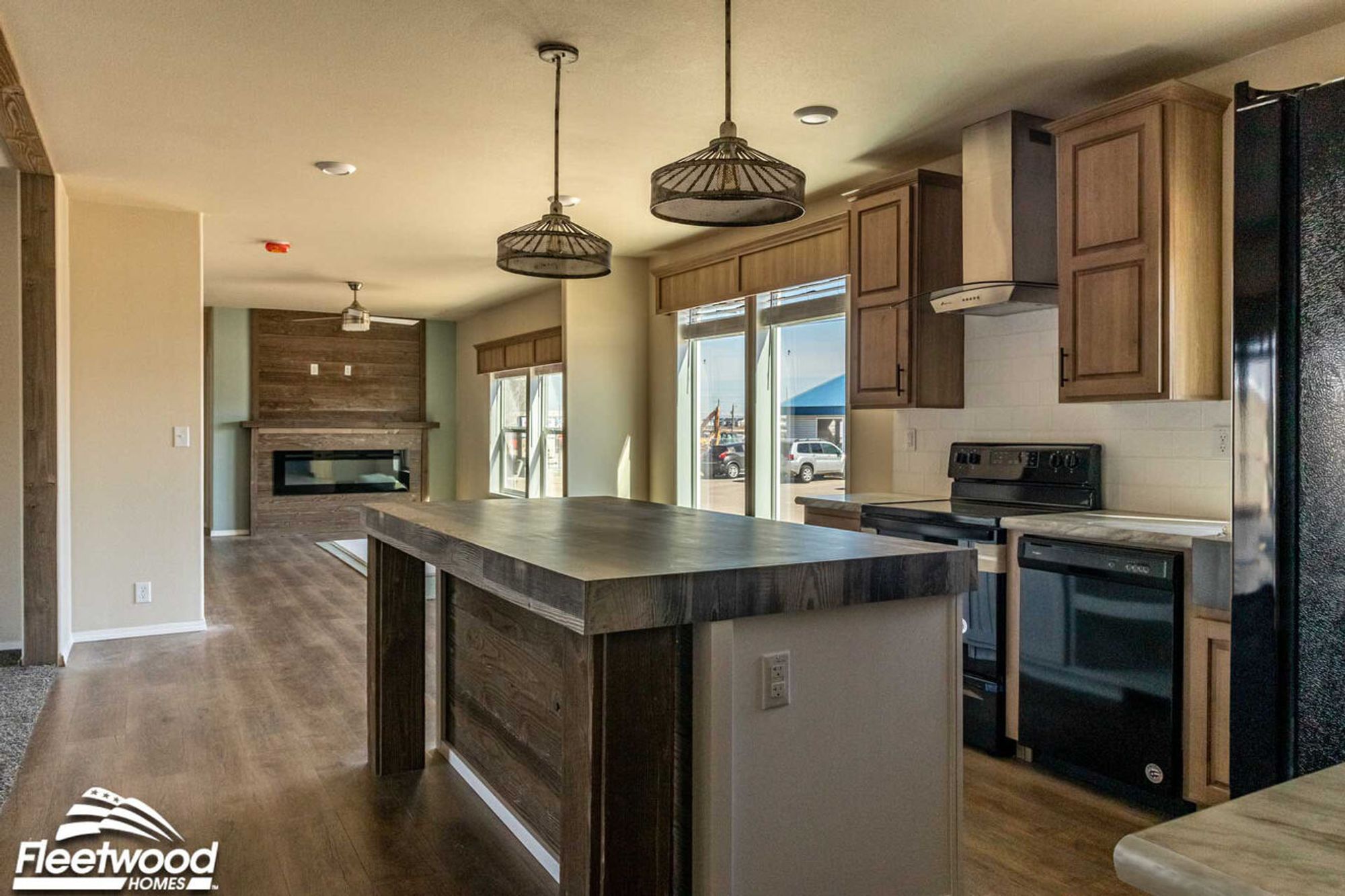 Kitchen with natural wood cabinetry, black appliances, farmhouse sink, and a rustic wood island with pendant lighting.
