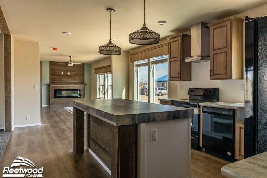 Kitchen with natural wood cabinetry, black appliances, farmhouse sink, and a rustic wood island with pendant lighting.