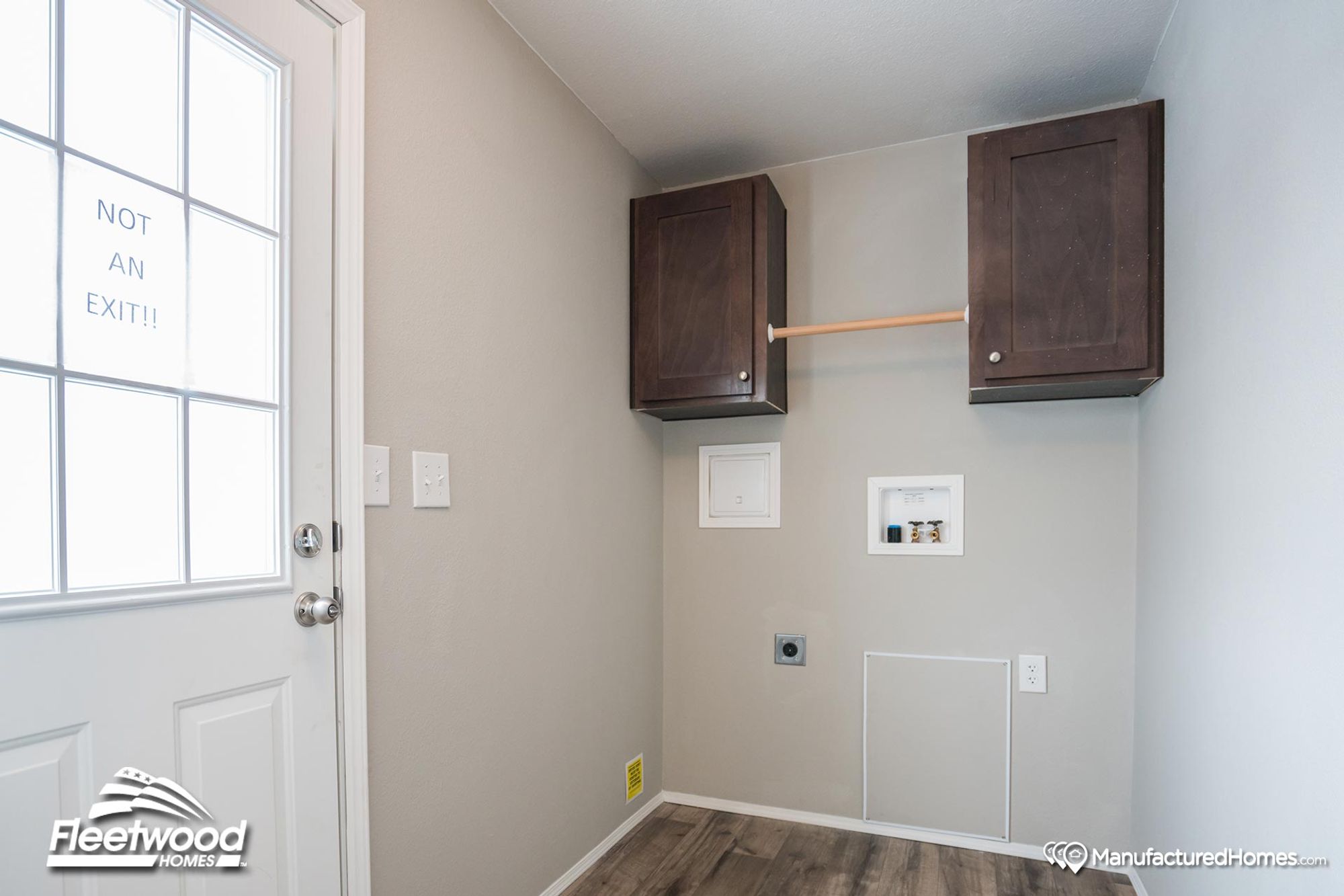 Laundry room with washer and dryer hookups, overhead dark wood cabinets, a hanging rod, and a white door labeled "Not an Exit" for utility space access.