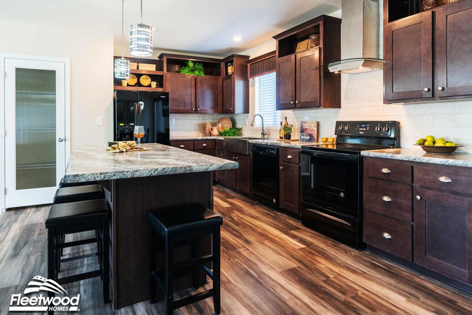 Kitchen, and living area with dark wood cabinets, center island, modern lighting.