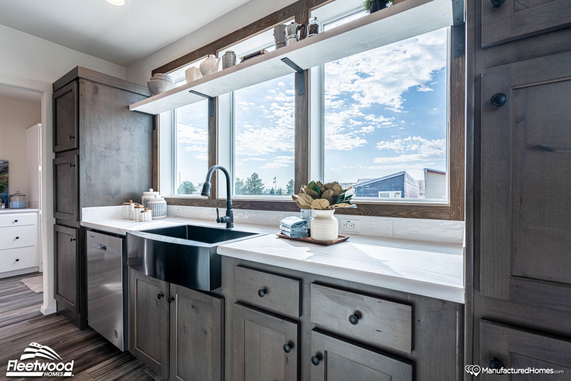 Close-up view of a kitchen’s farmhouse sink, adjacent countertops, and dishwasher.