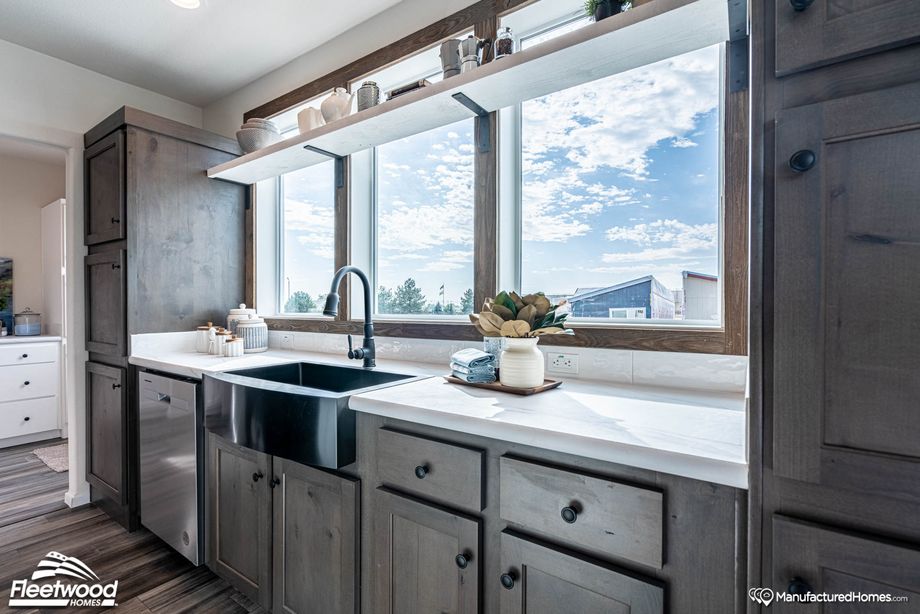 Close-up view of a kitchen’s farmhouse sink, adjacent countertops, and dishwasher.