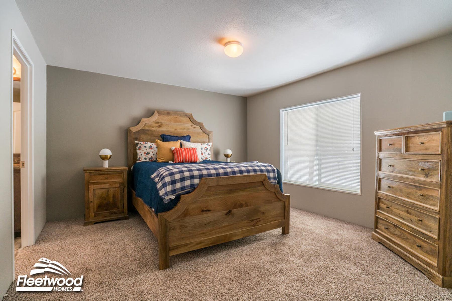 Cozy bedroom with rustic wood furniture, including a high headboard bed with blue plaid bedding, matching nightstand, and dresser on carpeted flooring.