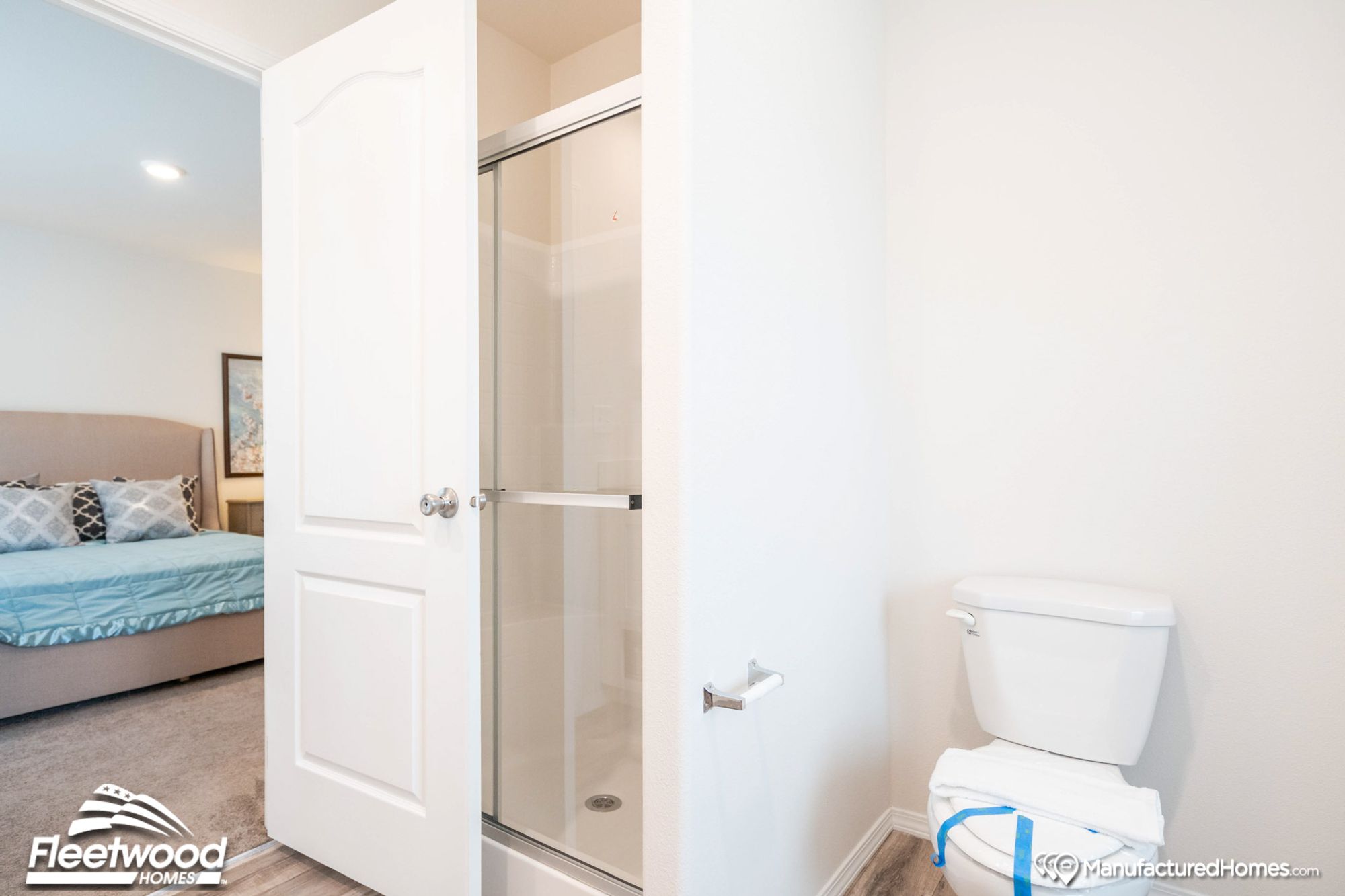 Partial view of a bathroom with a stand-up shower and a glimpse of a bedroom.
