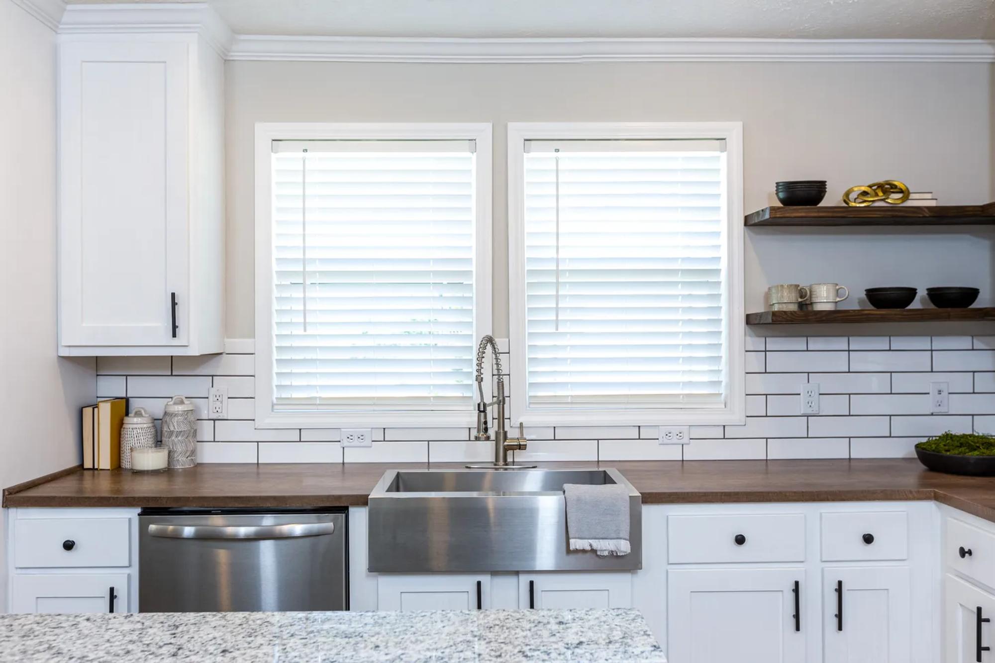 Close-up kitchen view of sink with brown countertops and white cabinets and drawers