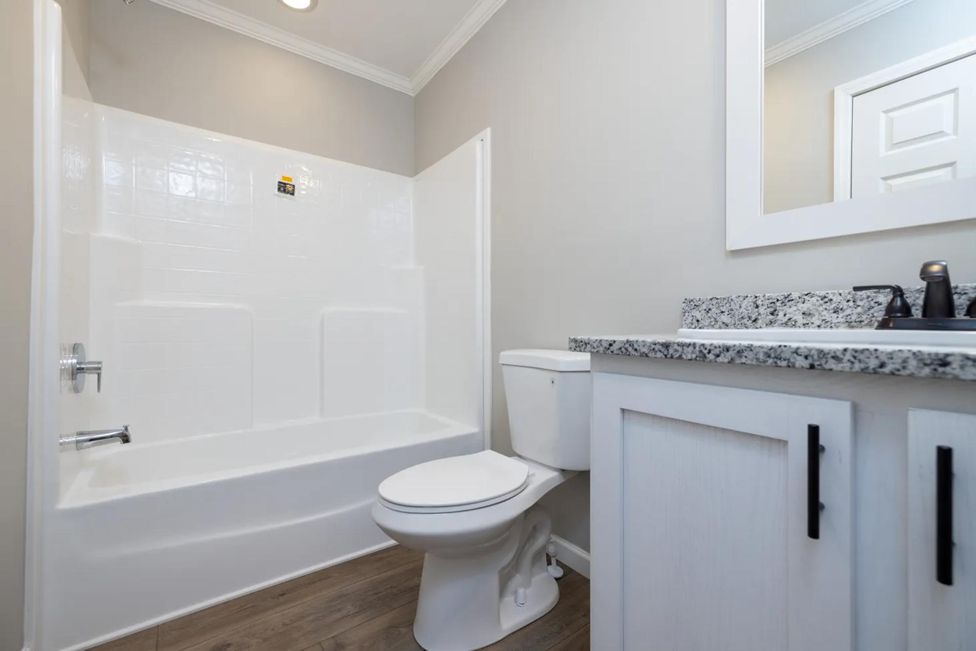 Full bathroom with white back-splashed shower and white-and-black speckled sink