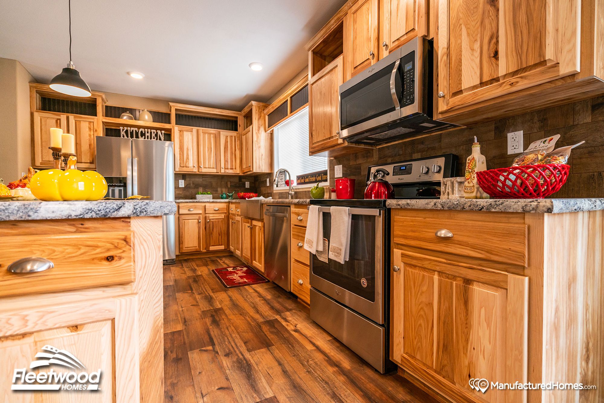 Large kitchen with a mix of light and medium warm wood cabinetry, and pepper-colored style countertops.