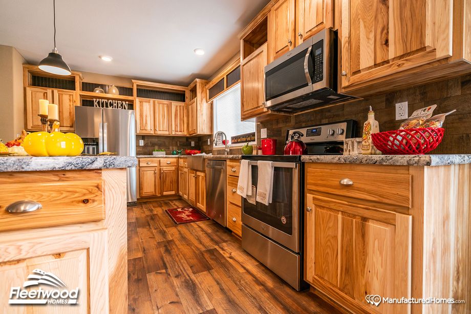 Large kitchen with a mix of light and medium warm wood cabinetry, and pepper-colored style countertops.