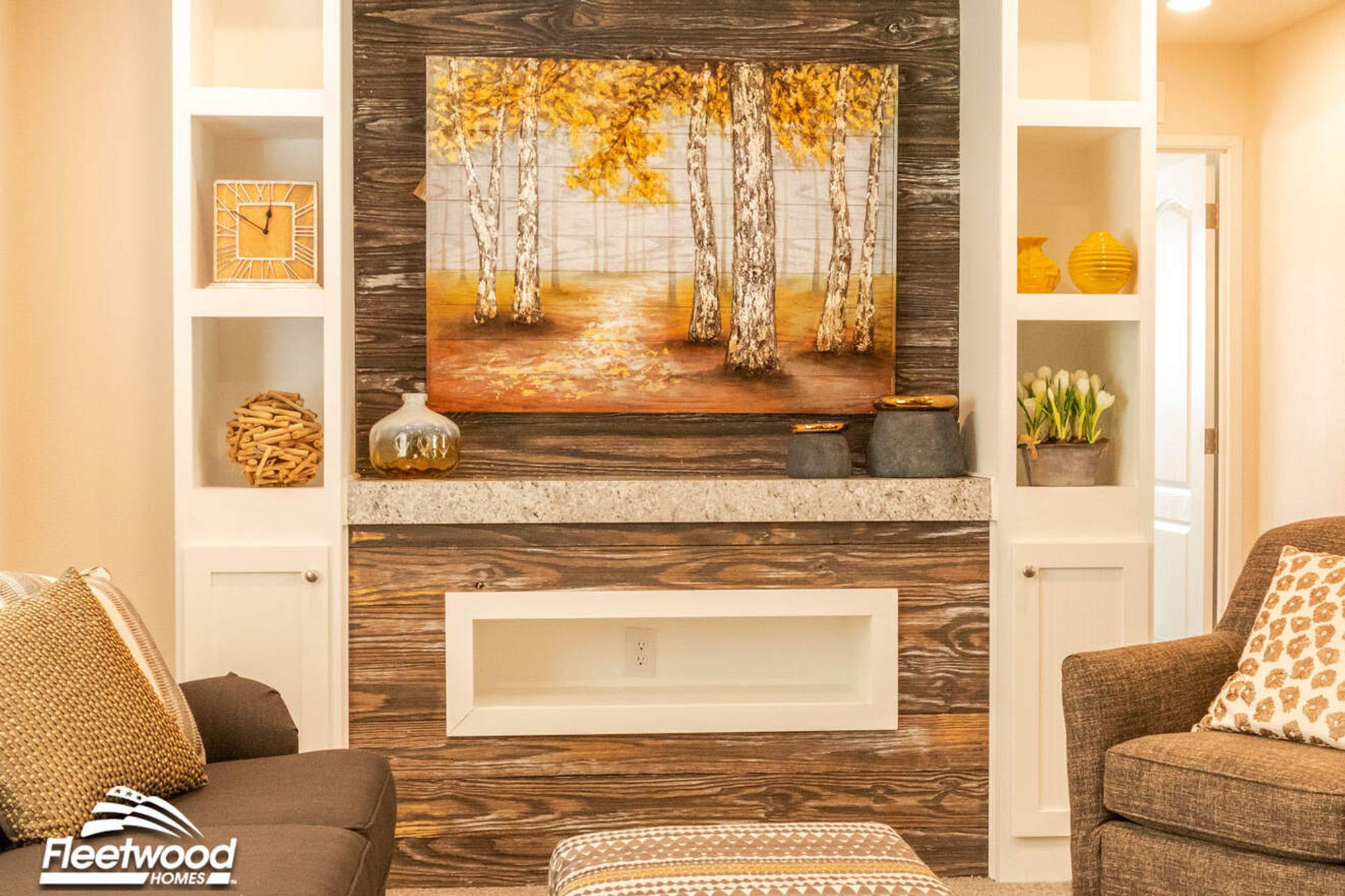 Feature wall with rustic wood paneling and a birch tree painting, framed by white built-in shelves displaying modern yellow and neutral decor accents.