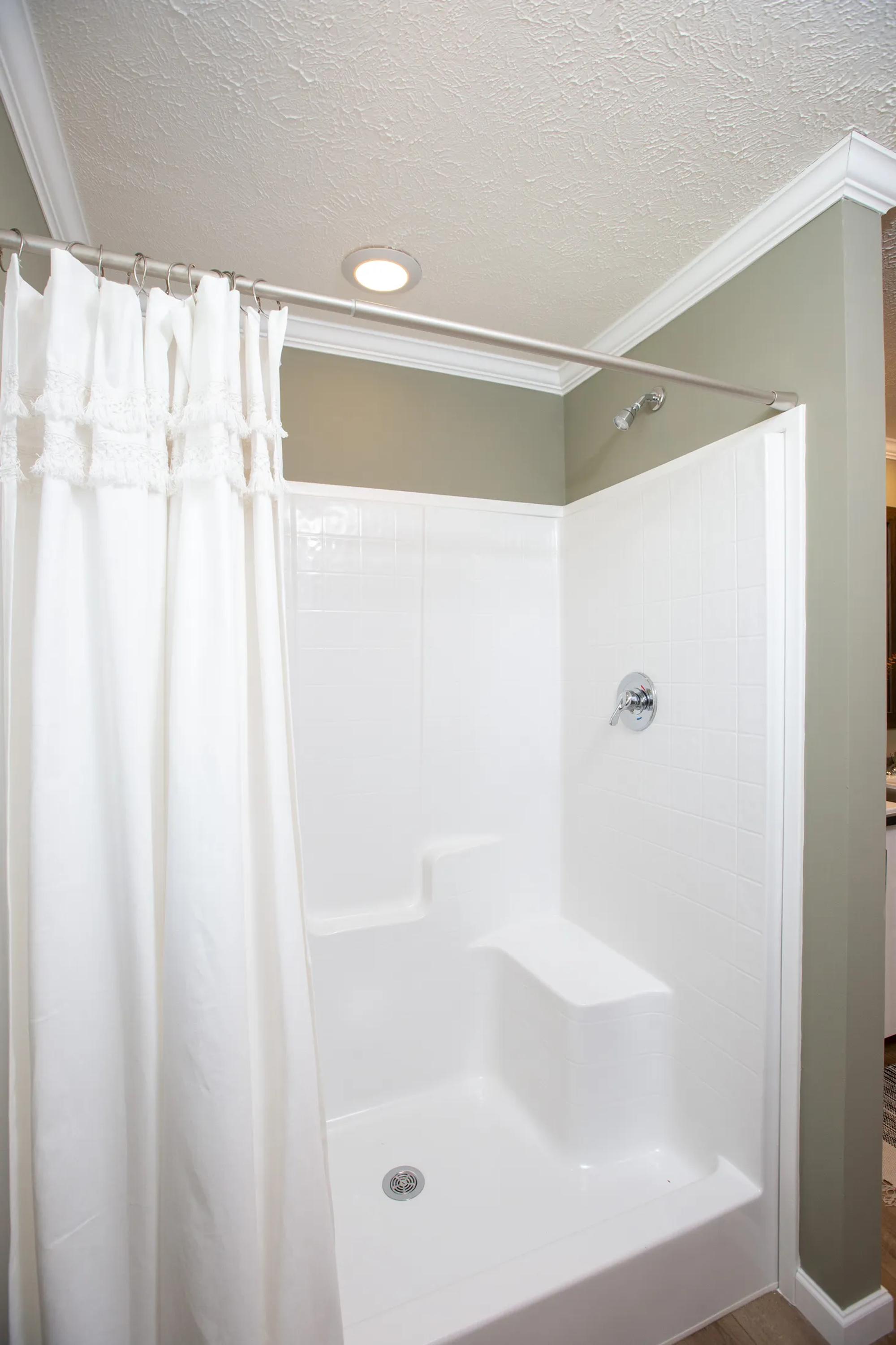 Close-up shot of white bathtub with white shower curtain