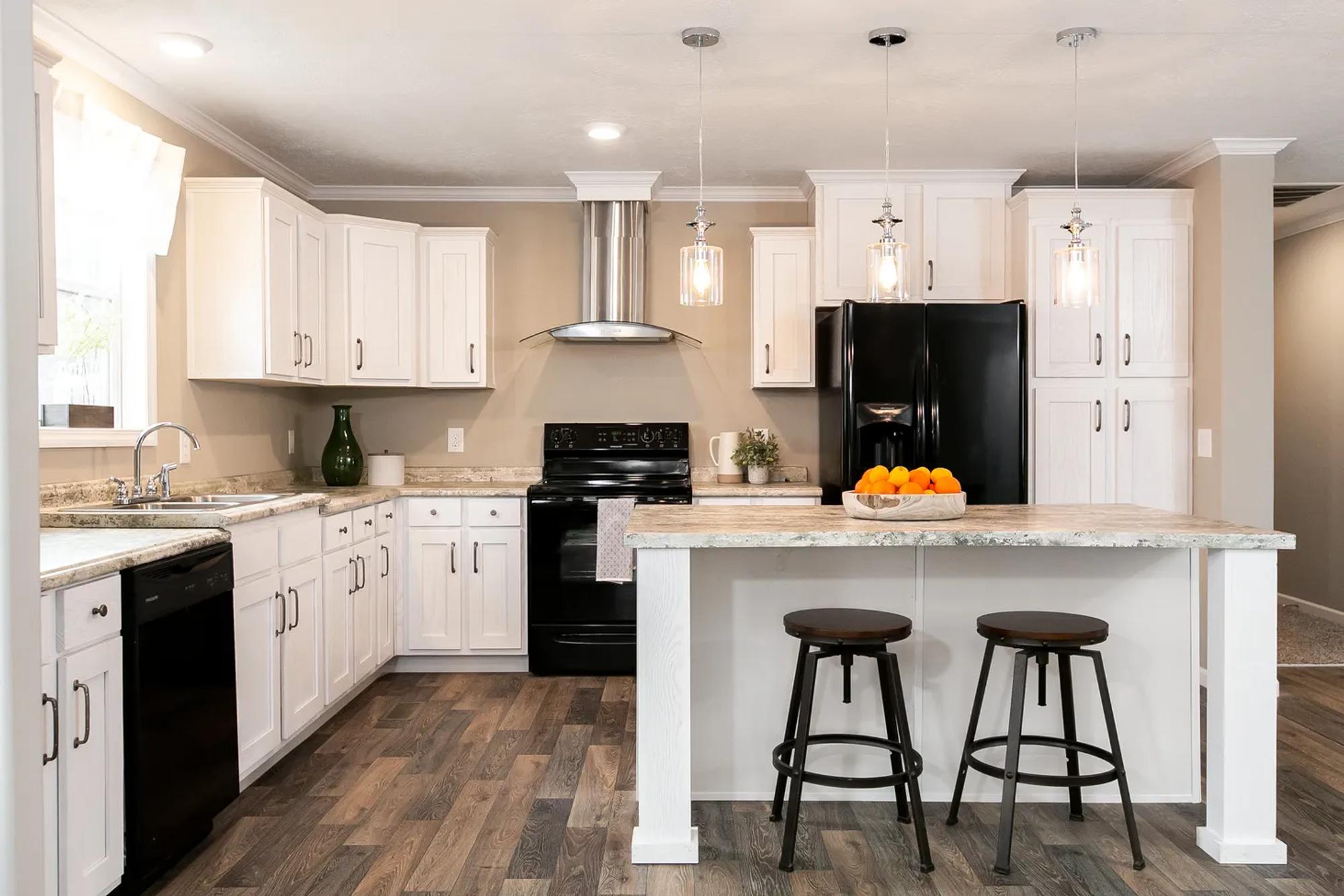 Large kitchen with black appliances and an island fitting two stools