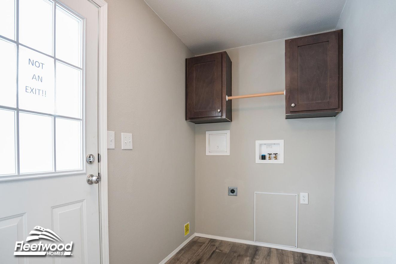 Laundry room with wood-look flooring, upper dark wood cabinets, washer and dryer hookups, and a door labeled “Not an Exit.”