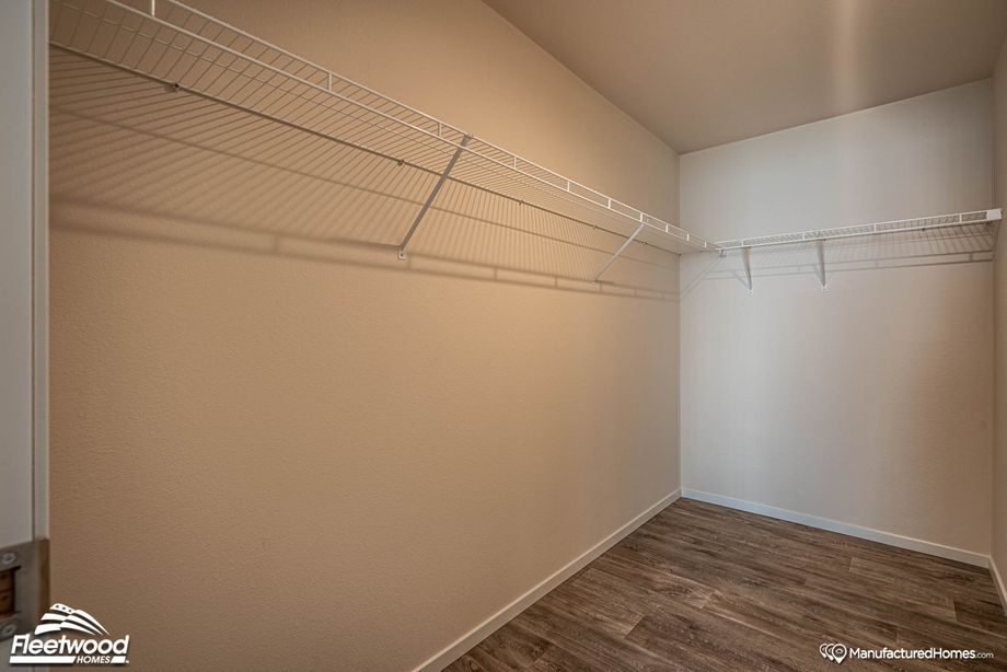 Large walk-in closet with white shelving lining the walls.