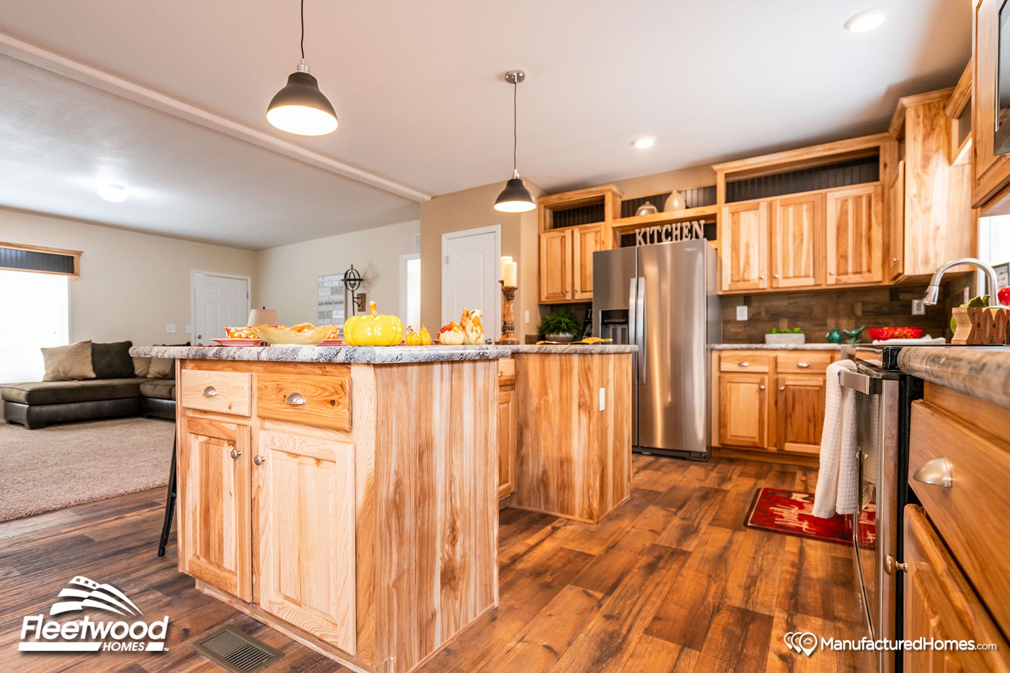 Large kitchen with a mix of light and medium warm wood cabinetry, and pepper-colored style countertops.