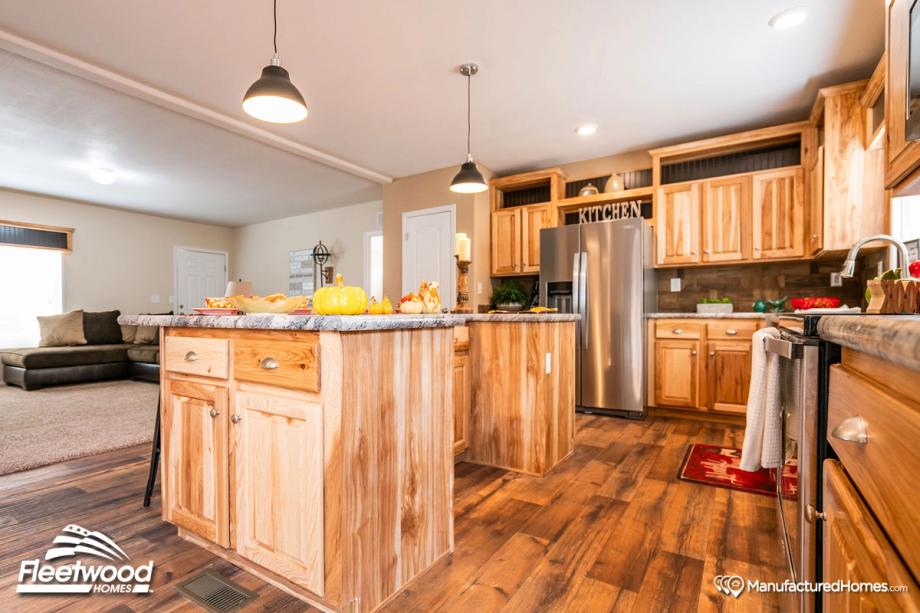 Large kitchen with a mix of light and medium warm wood cabinetry, and pepper-colored style countertops.