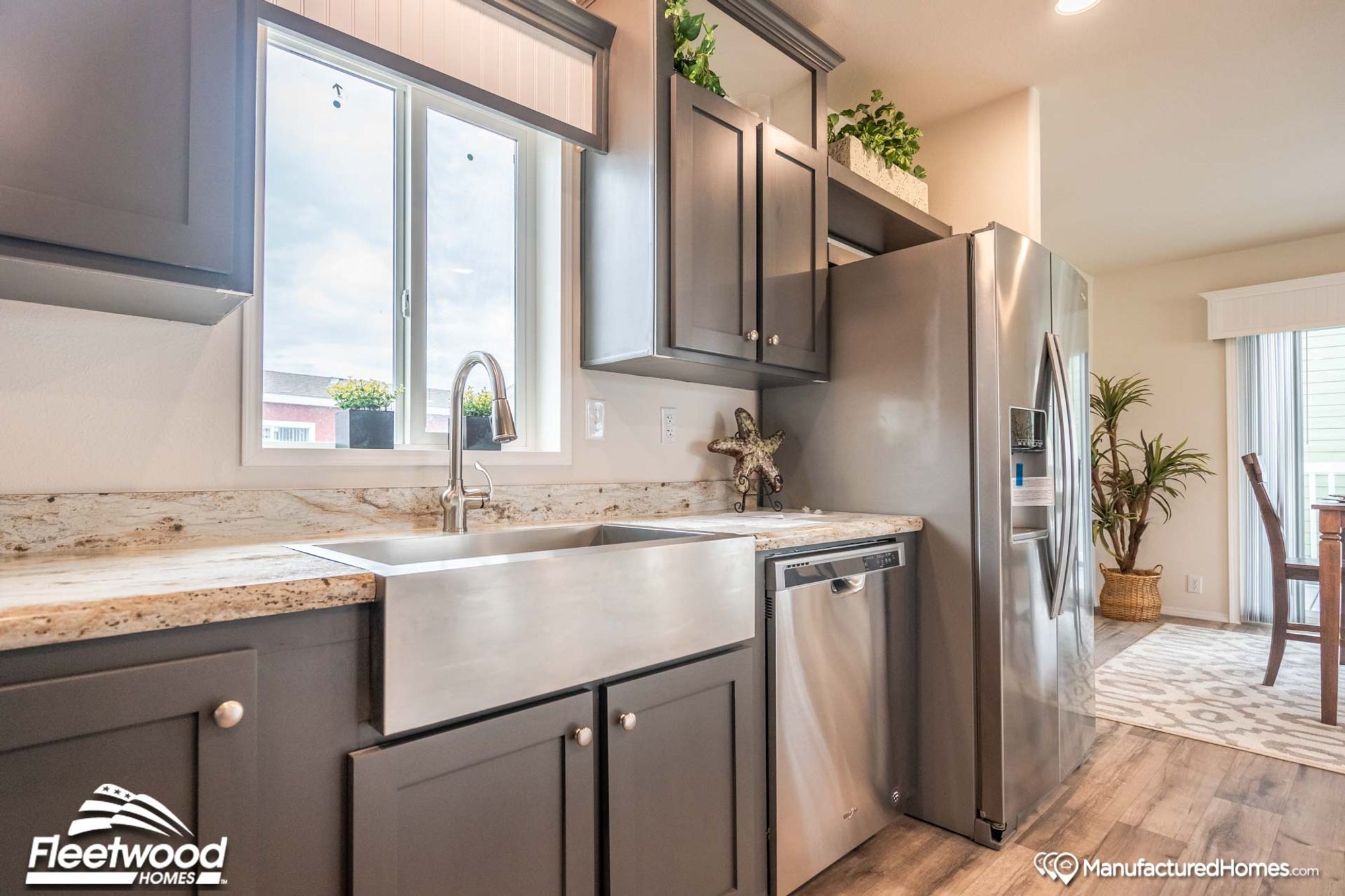 Close-up shot of a kitchen’s sink, adjacent counter space, cabinets above, and refrigerator.