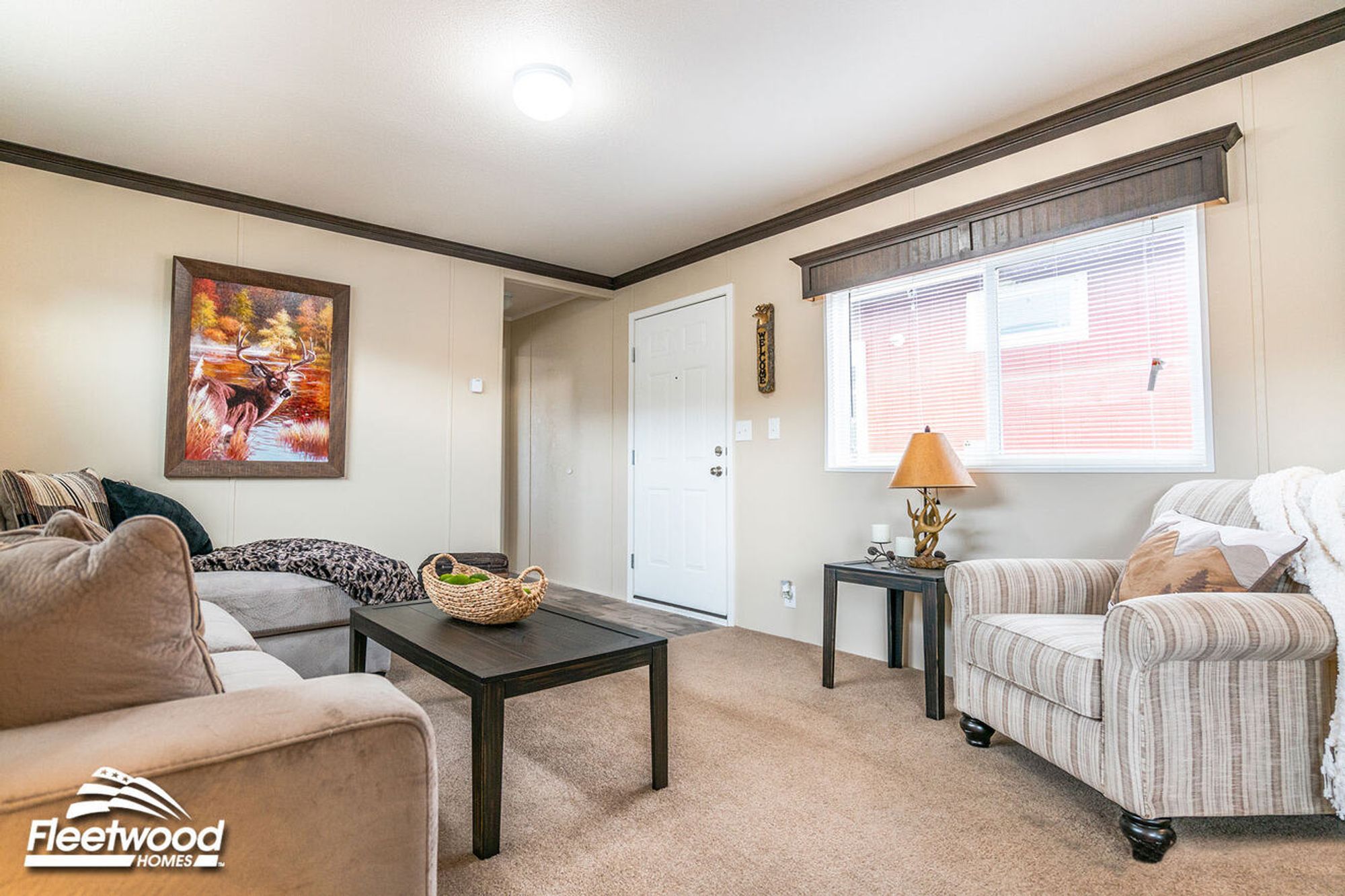 Cozy living room with a sectional sofa, striped armchair, dark wood coffee table, and deer artwork on the wall.