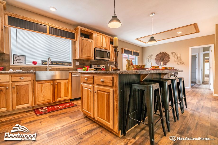 Large kitchen with a mix of light and medium warm wood cabinetry, and pepper-colored style countertops.