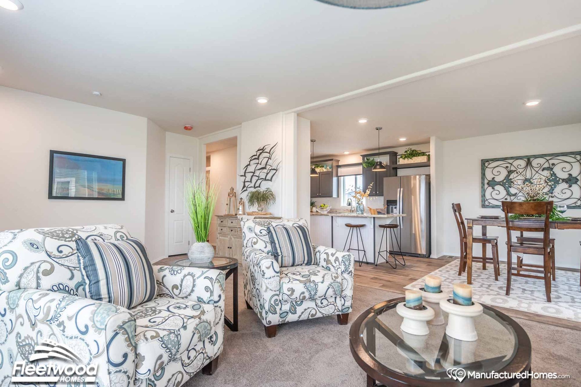 Open-concept living room, kitchen, and dining room, with the living room as the main focus featuring two chairs and a coffee table.