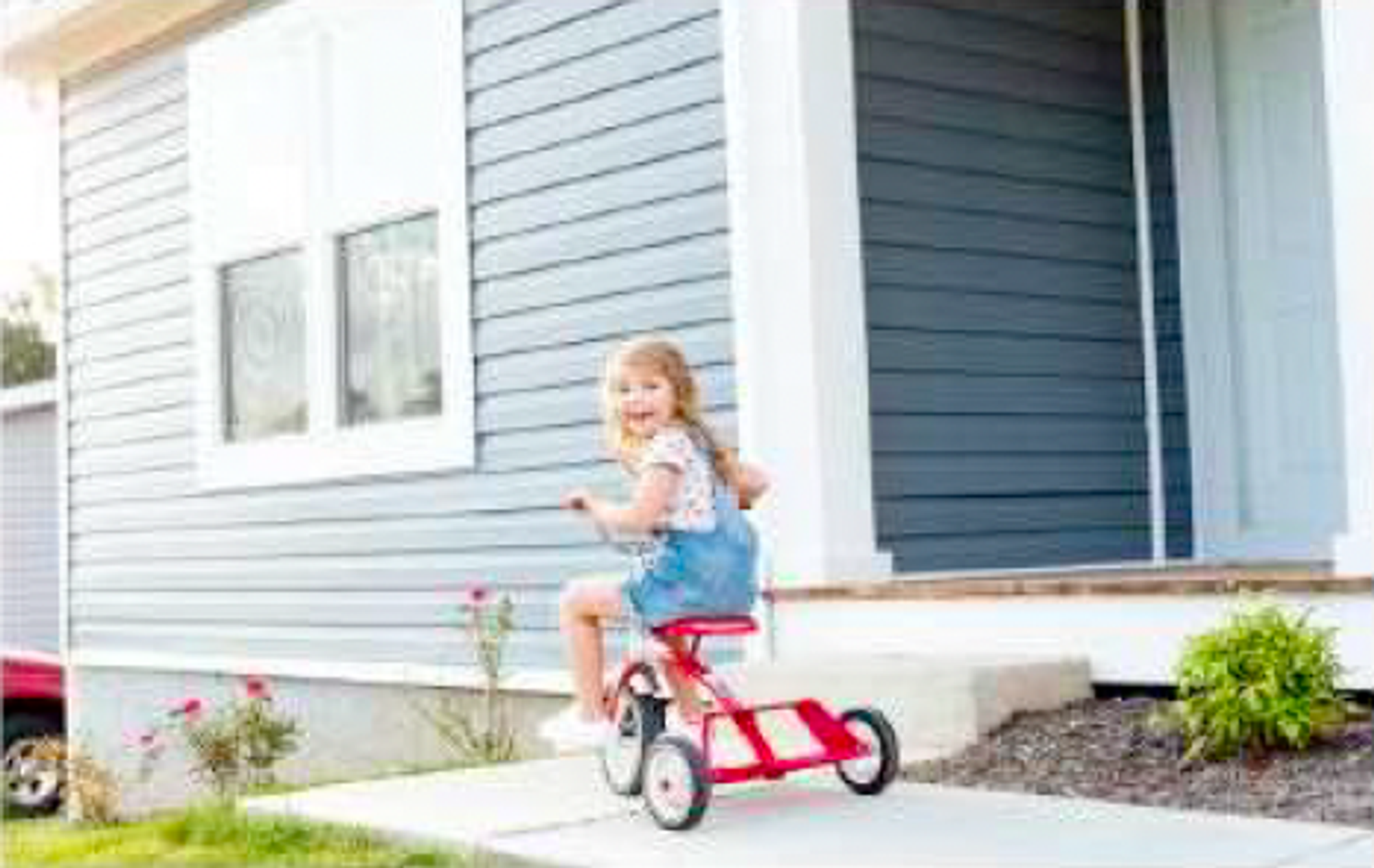 Little girl on a bike, in-front of the home