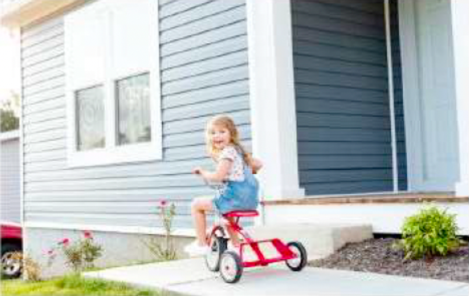 Little girl on a bike, in-front of the home