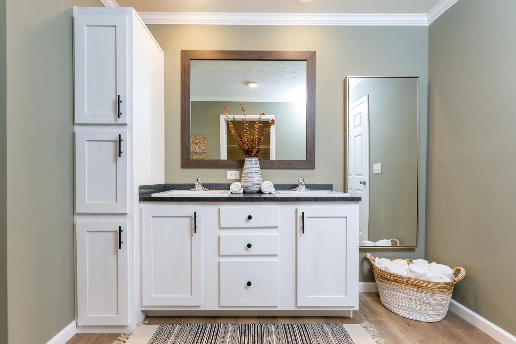 Bathroom with two double sinks, medium countertop, large white cabinet, mirror, and laundry basket