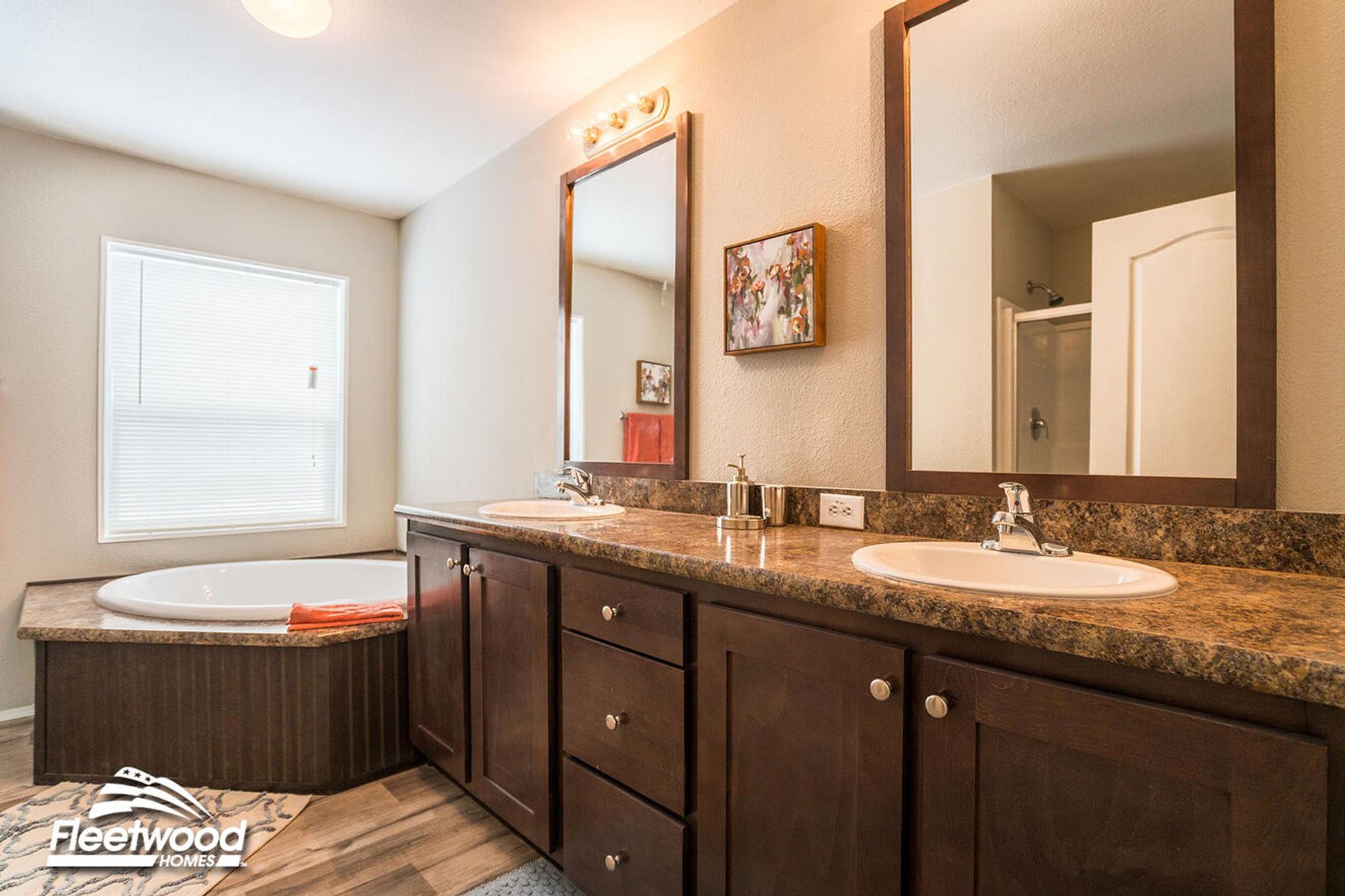 Spacious bathroom with dual sinks, brown marble countertop, corner soaking tub, and a separate walk-in shower partially visible in the background.