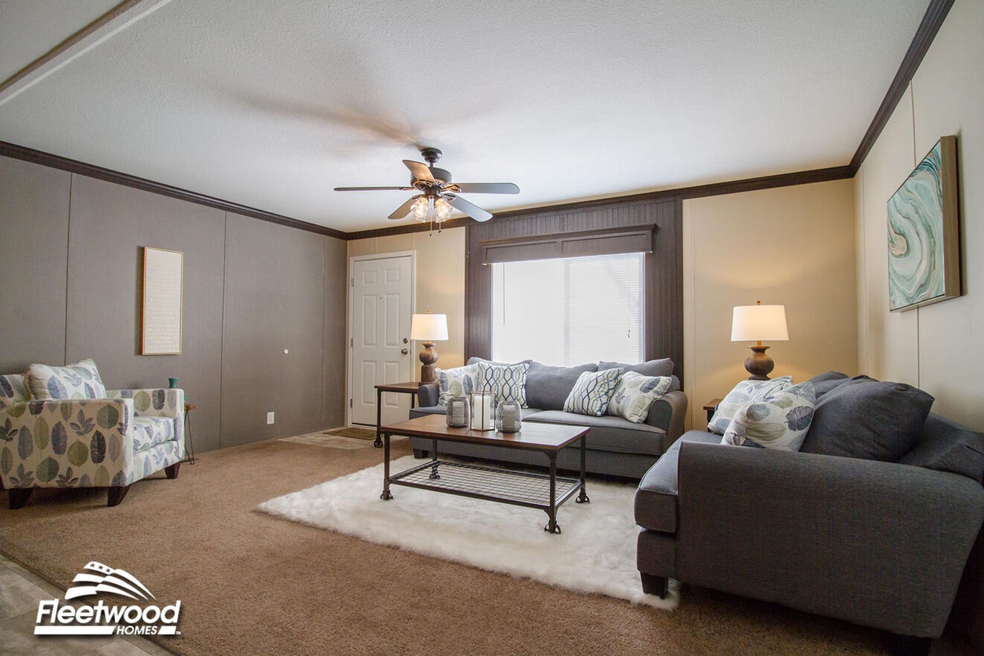 Living room with two gray sofas, an accent chair, coffee table on a white rug, and ceiling fan overhead.