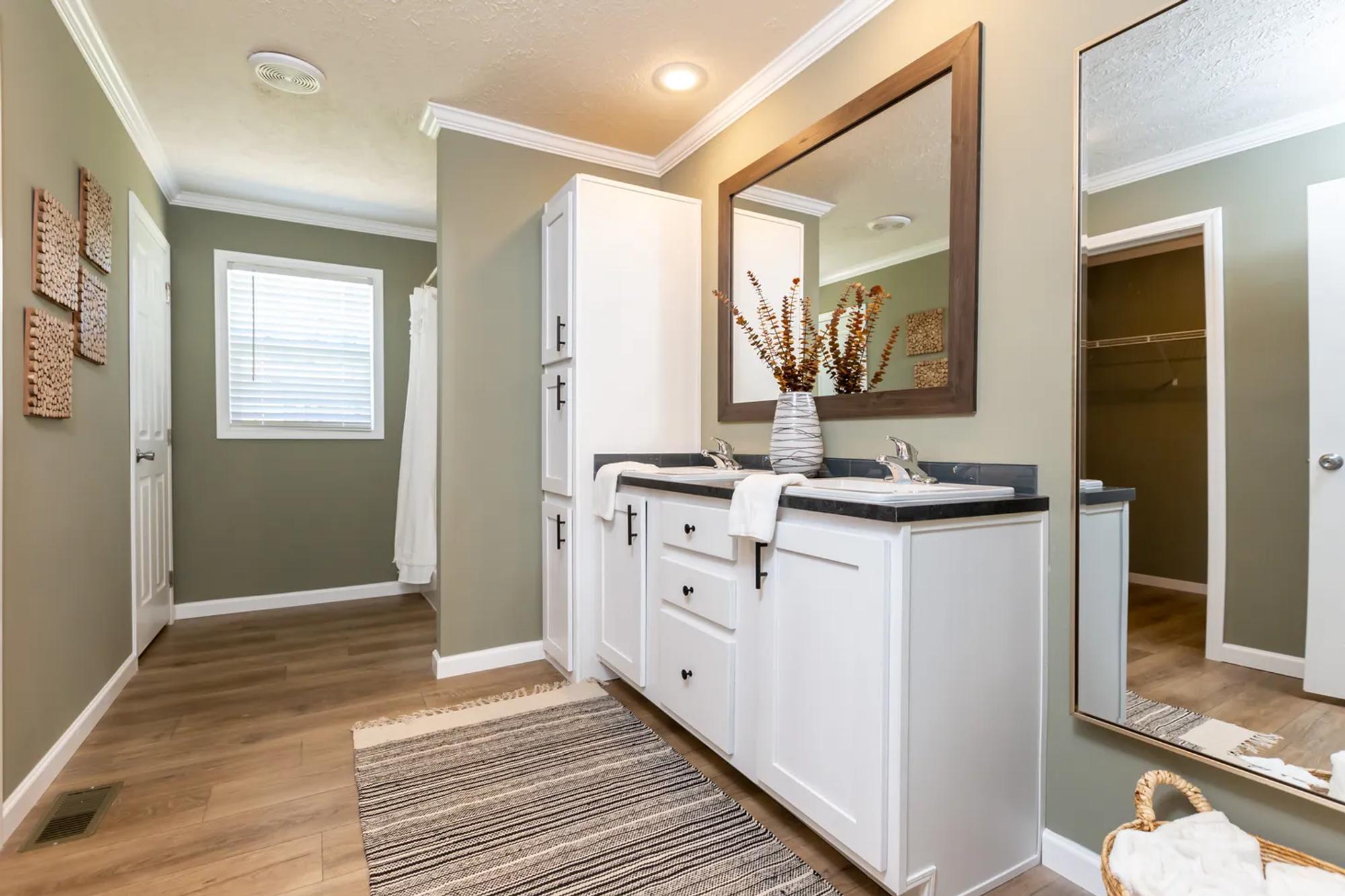 Long bathroom with green walls and double sinks on a medium-sized countertop